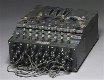 ENIGMA-- Calculating Machine. A three-rotor Enigma enciphering machine, number A-957, with electric core end stamped B above bulb board, raised 'QWERTZ' keyboard with crackle black painted metal case (some restoration), three division window flap over rotors and concealed plugboard in the front with twelve patch leads, in carrying case, circa 1939. 10 in (26cm) wide, also with metal label Chiffriermaschinen Gesellschaft Heimsoeth und Rinkew on  the inside of the lid -0.5in (2.5cm) high