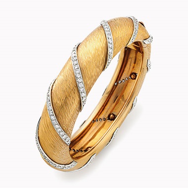 A gold and diamond bangle bracelet, by Bulgari. The hinged bangle designed as a textured 18k-gold bracelet, intersected by diagonal platinum and circular-cut diamond rows, diameter 2½ in. Estimate $5,000-7,000. This lot will be offered in The Private Collection of President and Mrs. Ronald Reagan, 21-22 September at Christies in New York