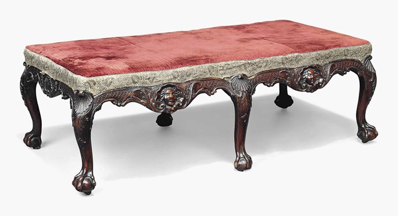 An Irish George II mahogany long stool, circa 1740. Covered in plum-coloured velvet with silvered thread braiding, the frame carved with masks within a trelliswork ground, the cabriole legs headed by carved scallop shells and acanthus leaves, on claw-and-ball feet and recessed castors. 16½ in (42 cm) high; 50 in (127 cm) wide; 28 in (71 cm) deep. Sold for £58,750 on 18 November 2015