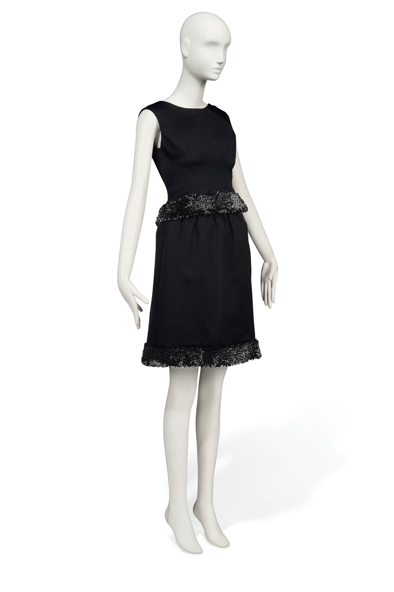 Charade, 1963
a cocktail gown of black satin, Givenchy couture, the two piece ensemble comprising a fitted bodice and skirt, each with a hem of semi-tubular black paillettes, set on edge, with multiple canvas tags to the interior, as well as black woven label with canvas tag inscribed 23174, designed for Audrey Hepburn as Regina Reggie Lampert in the 1963 Universal production Charade. Estimate