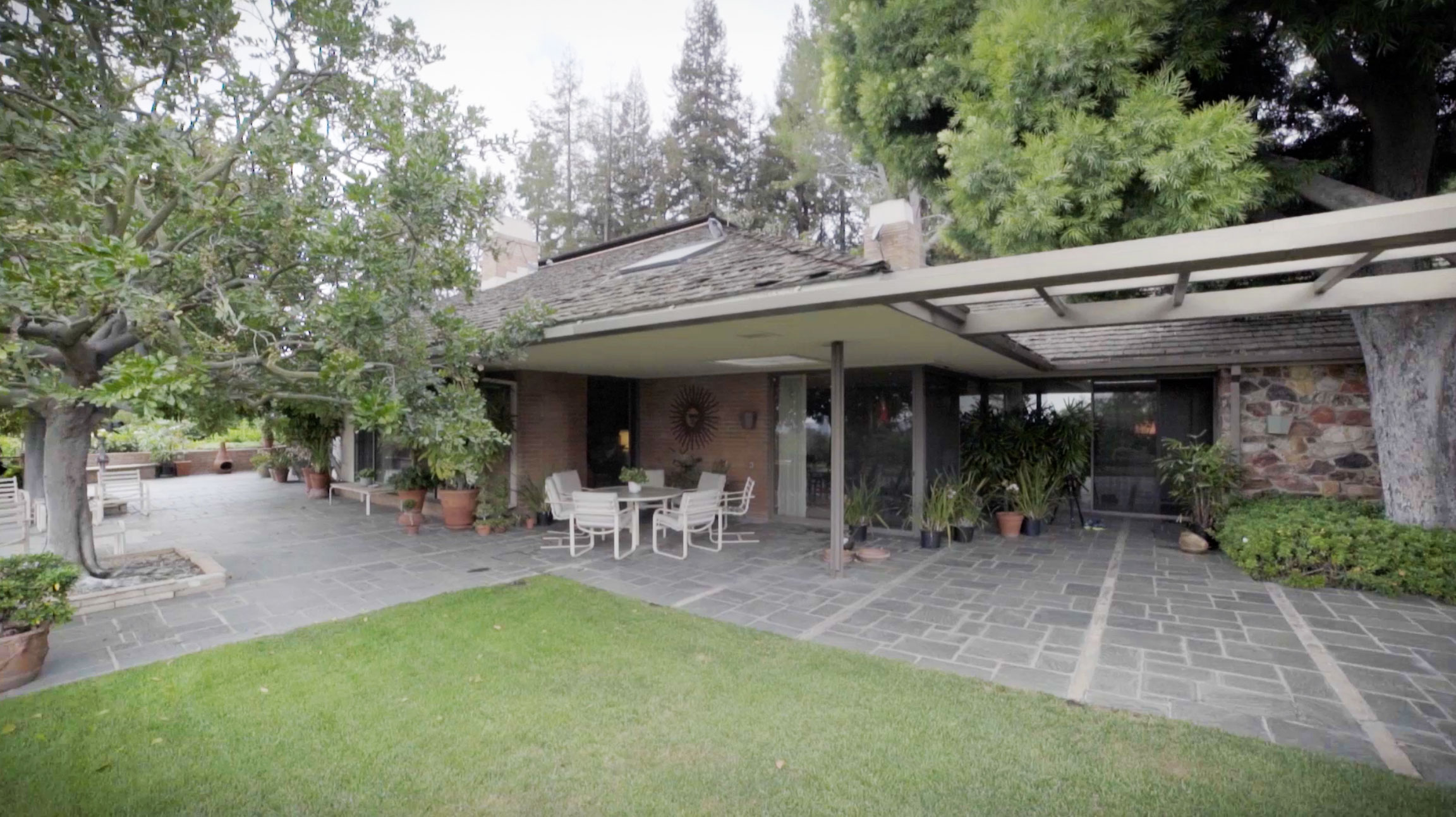 Located at the top of a bougainvillea-lined driveway, the house is set in lush gardens with views of downtown Los Angeles and Century City