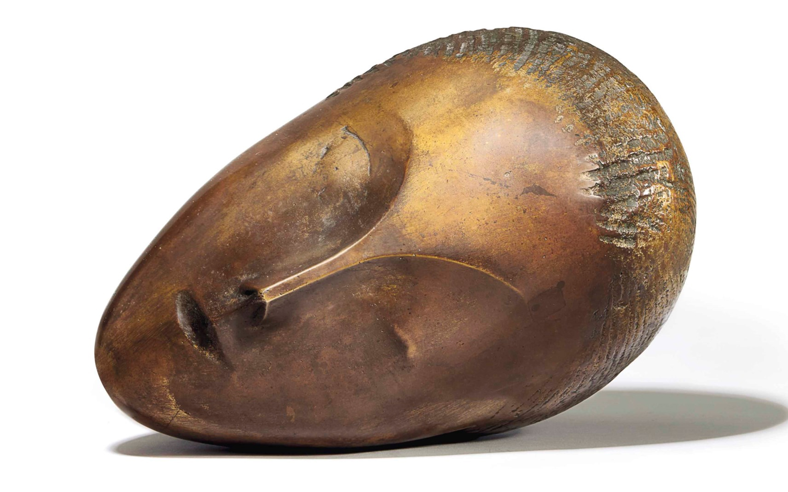 A smooth bronze sculpture of a stylized head resting on its side with minimal facial features.
