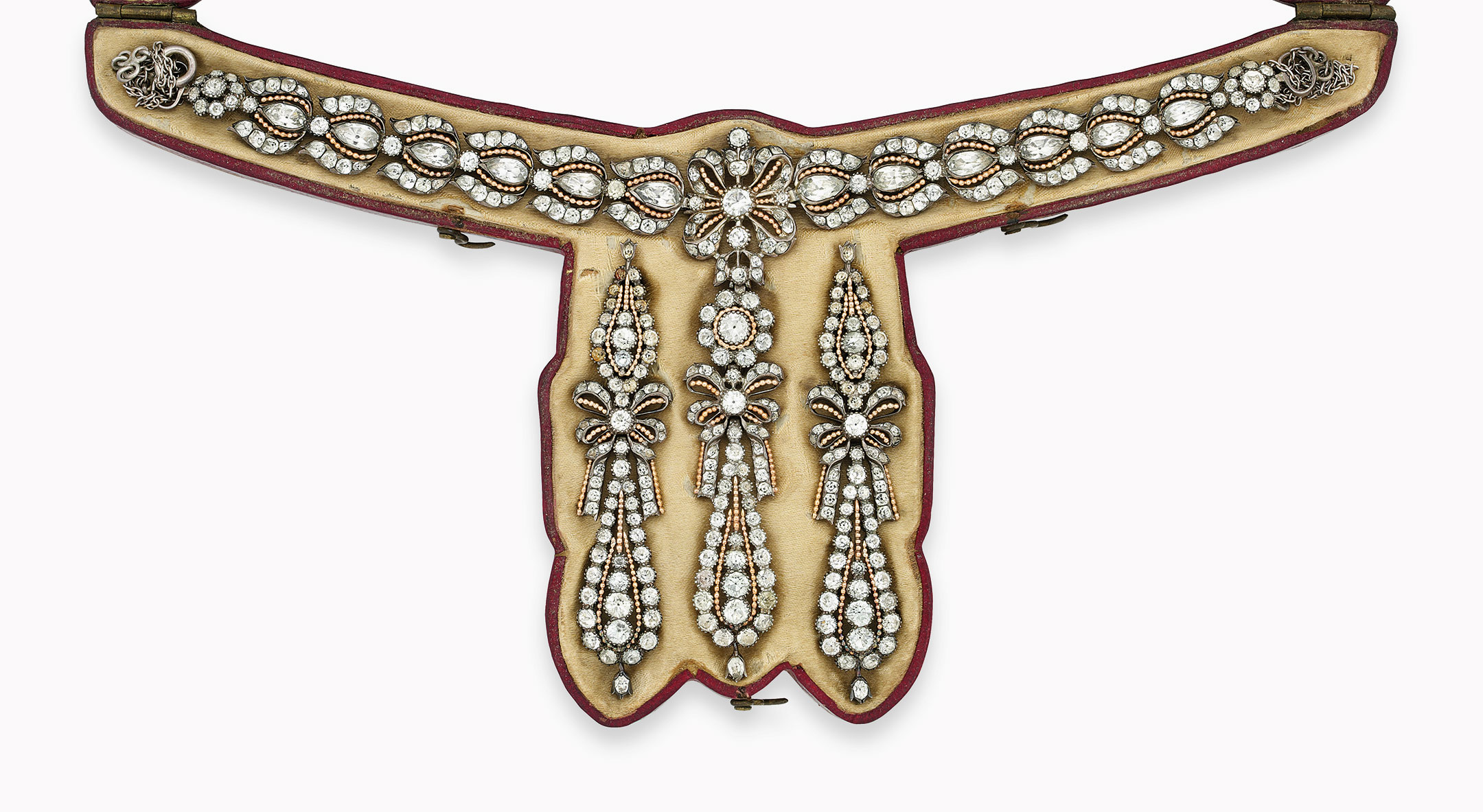 A late 18th-century Portuguese topaz demi-parure. The necklace composed of a series of stylised bud-shaped panels, each set to the centre with a pear-shaped topaz within a similarly-set vari-cut border to the central bow motif, suspending a detachable pendant with similarly-set flowerhead cluster and a bow motif panel, foil-backed in silver, together with a pair of ear pendants en suite, circa 1770. Estimate: £12,000-15,000. This lot is offered in Important Jewels on 13 June at Christie’s London