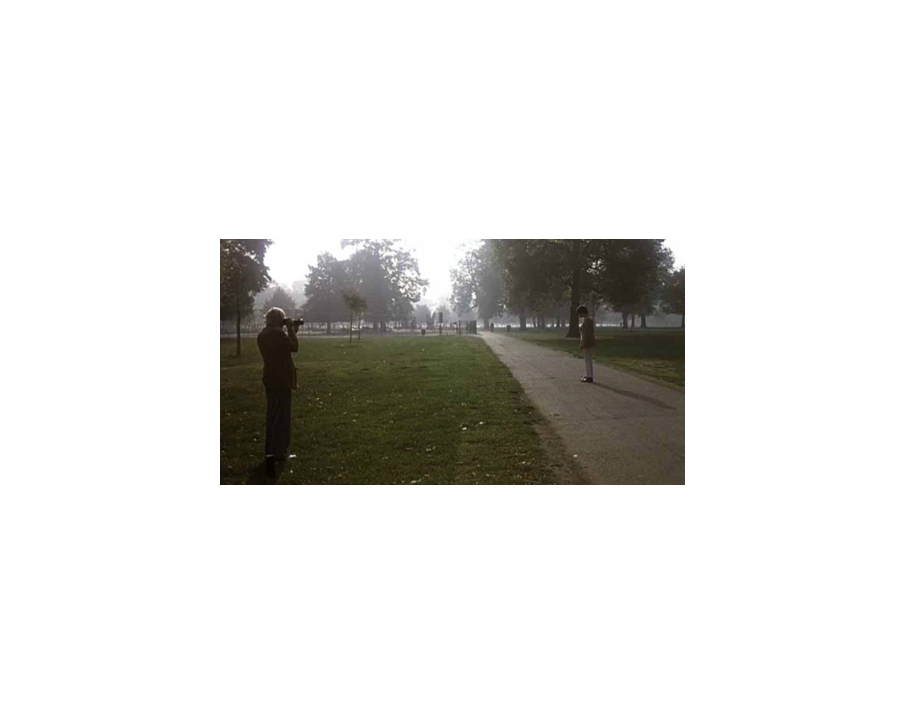 霍克尼在倫敦肯辛頓花園為其伴侶彼得·施萊辛格拍照,並由此創作了作品裡站在泳池邊、身穿粉紅色外套的人像。《危情後樂園》電影劇照,1974年。攝影:Jack Hazan / Buzzy Enterprises Ltd