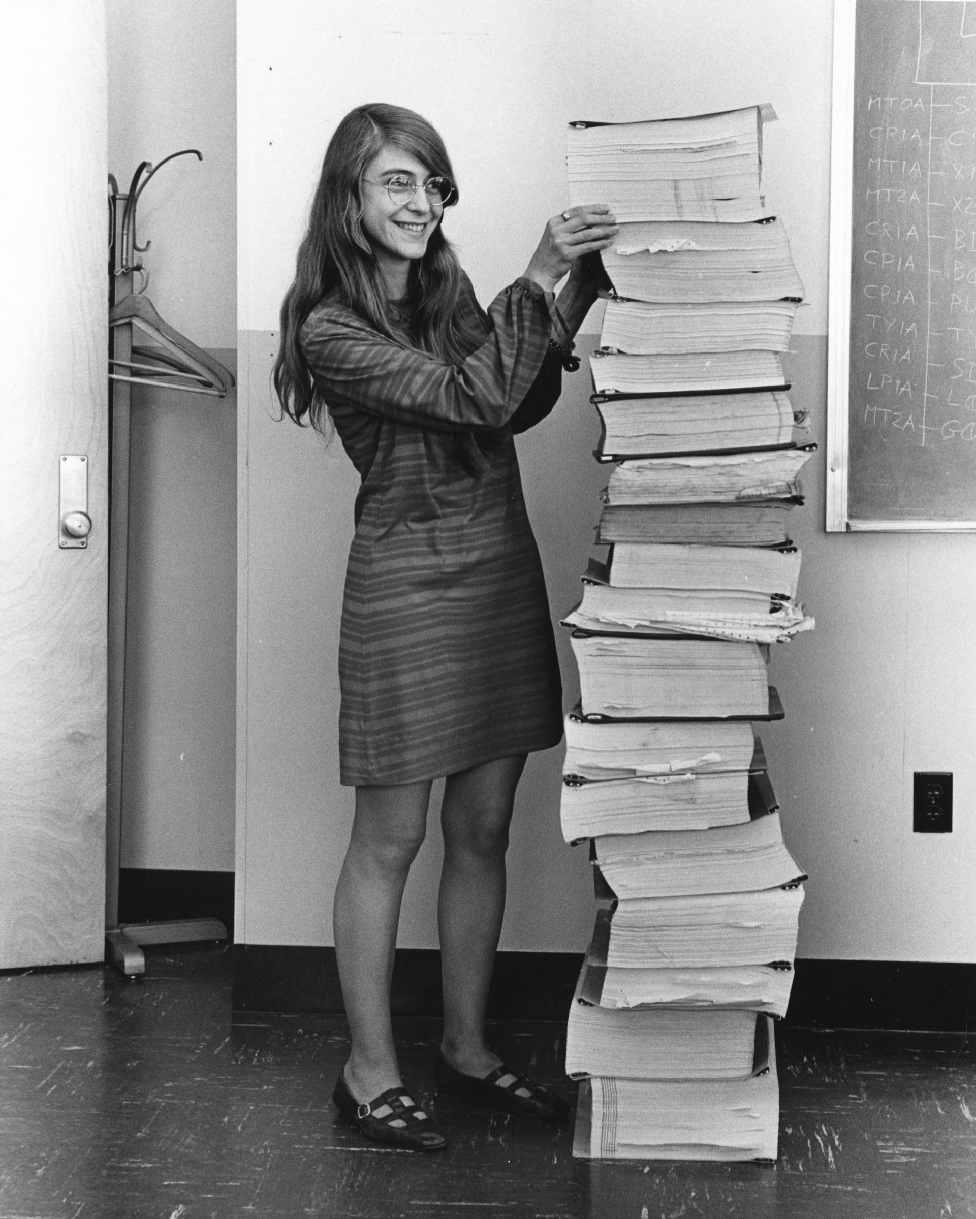 Margaret Hamilton photographed in 1969, standing next to a stack of code print-outs for Apollo in-flight software