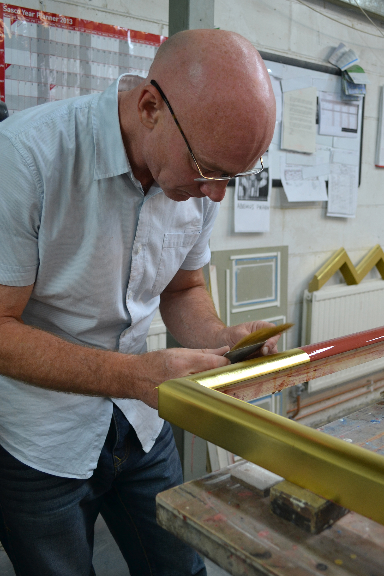 Gilder applying gold leaf to gesso frame. © John Jones London