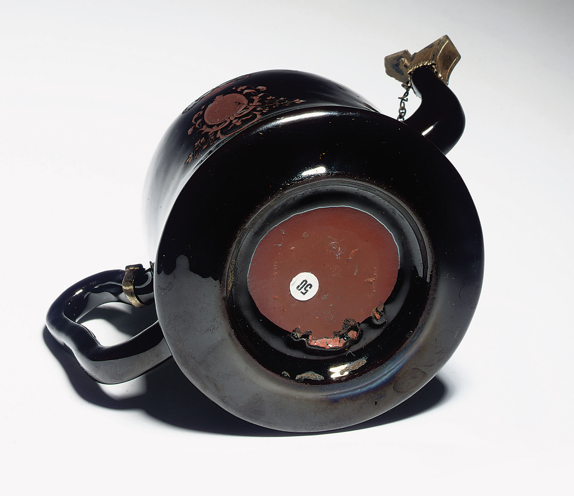 On the underside of this Böttger teapot and cover from circa 1710-11 the glaze does not cover the base, and there is evidence (lower right) of iridescence