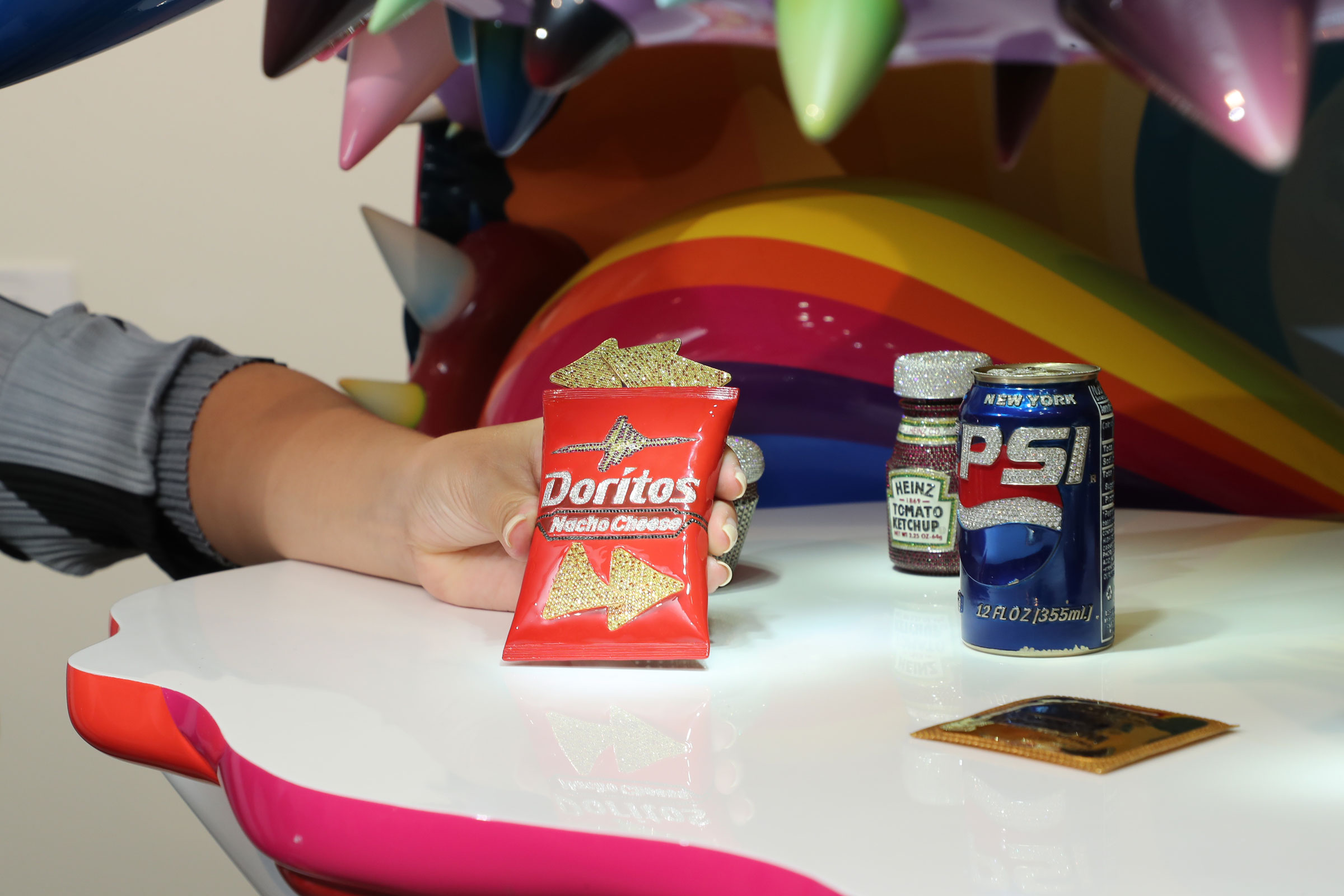 Objects contained within The Simple Things (2008-2009) include replicas of a bag of Doritos and a can of Pepsi — fashioned from gold and thousands of precious gems