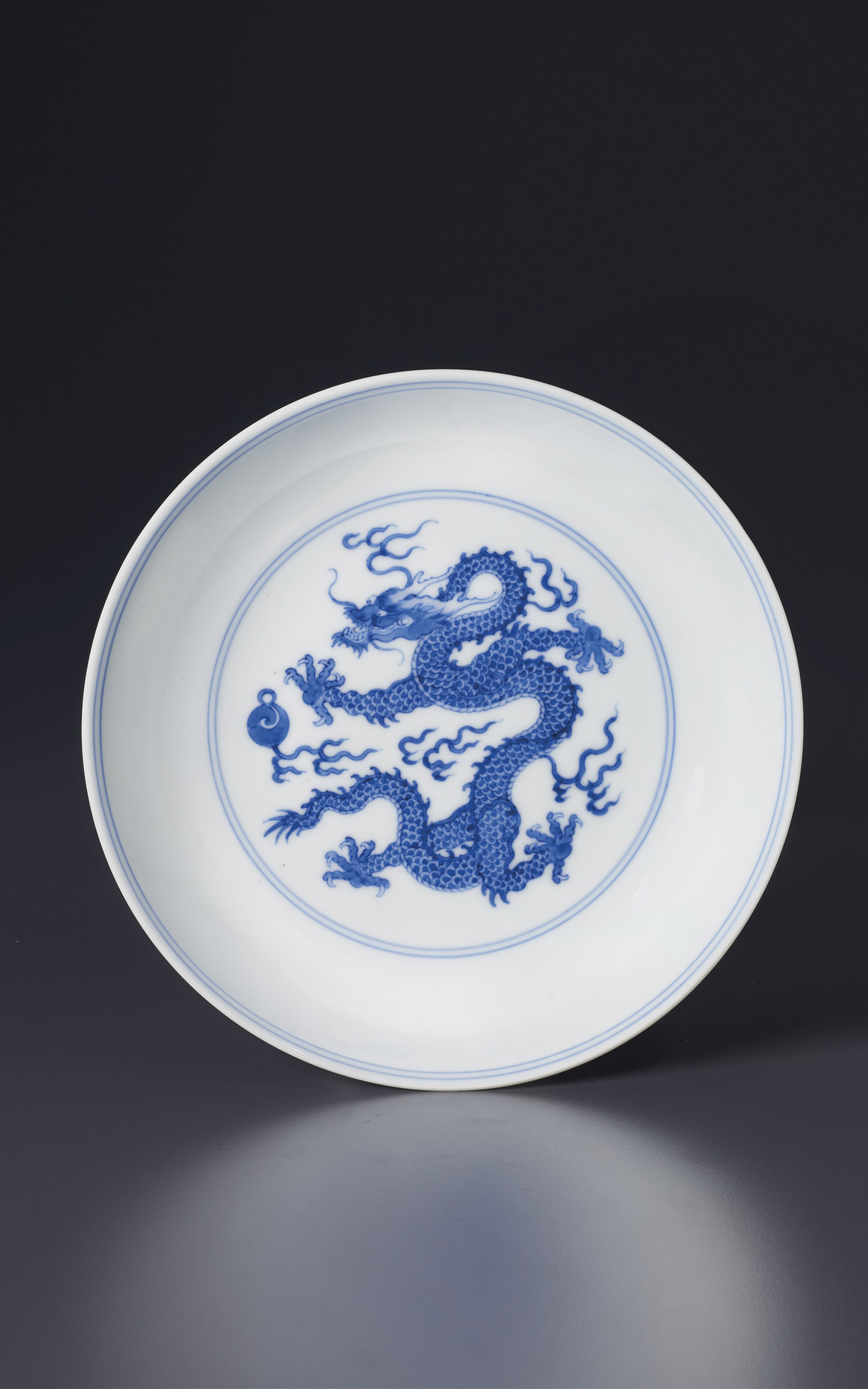 A blue and white 'Dragon' dish, China, Qing dynasty, Yongzheng six-character mark in underglaze blue within a double circle and of the period (1723-1735). 7⅛ in (18.2 cm)  diam. Estimate: $30,000-50,000. Offered in Sacred and Imperial: The James and Marilynn Alsdorf Collection Part II on 24 September at Christie’s in New York