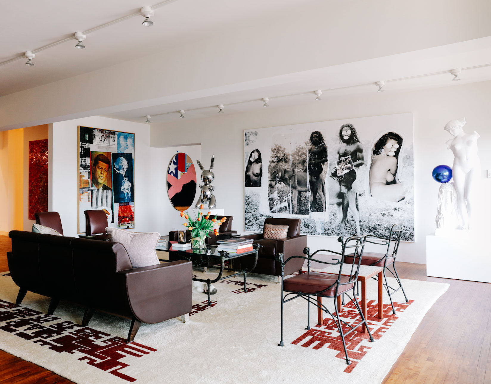 A sitting room with works by artists including Robert Rauschenberg (Retroactive II, 1963), Tom Wesselmann (Great American Nude #41, 1962), Jeff Koons (Rabbit, 1986 and Gazing Ball (Esquiline Venus), 2013), Richard Prince (Back to the Garden, 2008) and Ron Mueck (Dead Dad, 1997-97), and a table and chairs by Diego Giacometti