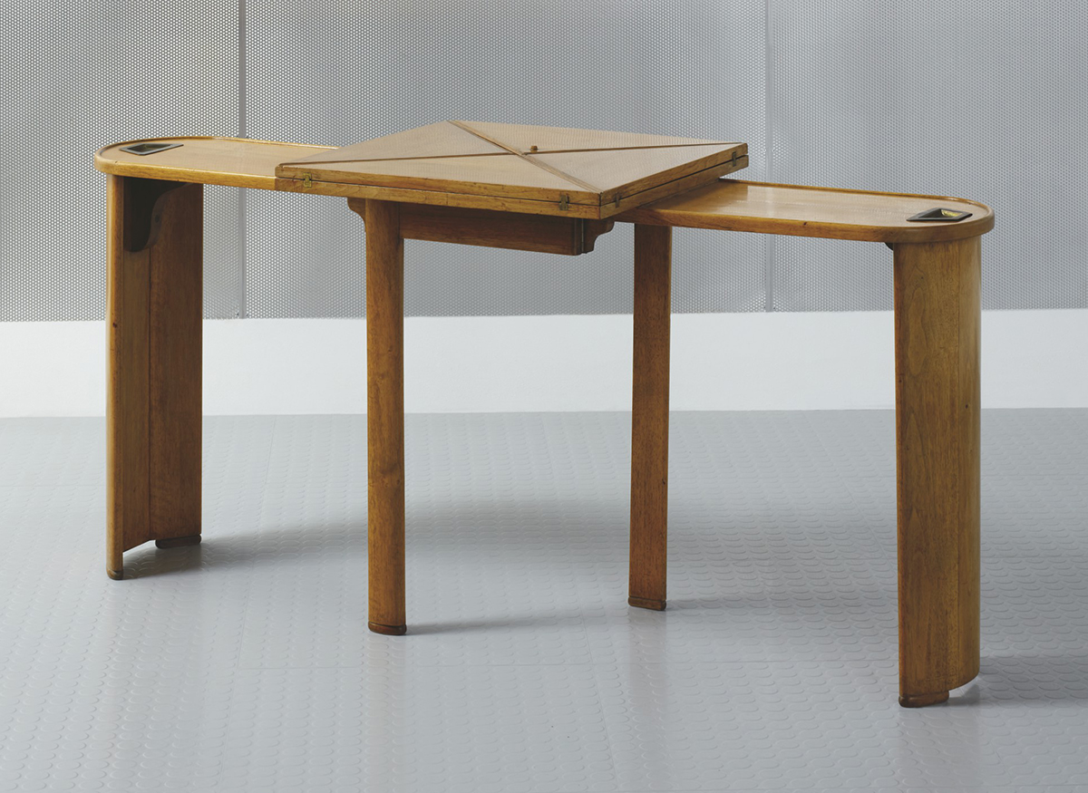 Pierre Chareau (1883-1950), Table de jeu mouchoir ‘MB 241a’, vers 1926. Walnut, brass, felt and partly gilt leather. Extended:  26⅜ x 57 x 41 in (67 x 145 x 104 cm). Folded: 27⅛ x 57 x 26⅝ in (69 x 145 x 52.5 cm). Estimate: €80,000-120,000. Offered in Annie et Jean Dalsace, Les collections de la Maison de Verre on 7 October 2021 at Christie’s in Paris