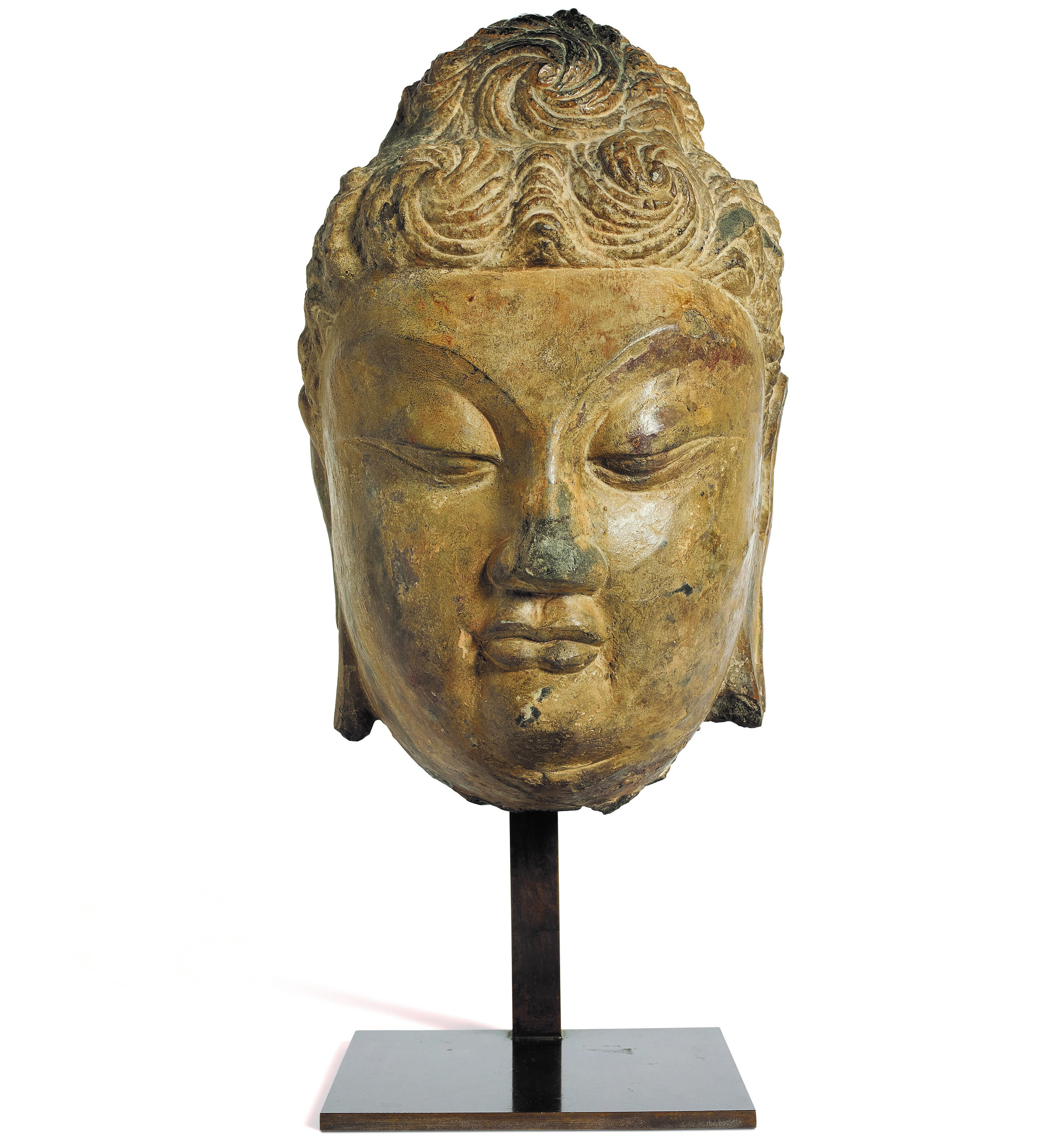 Stone buddha head, China, Yuan-Ming Dynasty (1279–1644) or earlier. H: 35.5 cm (14 in), metal base. Estimate: €30,000-40,000. Offered in Collections on 28 October at Christie’s Paris