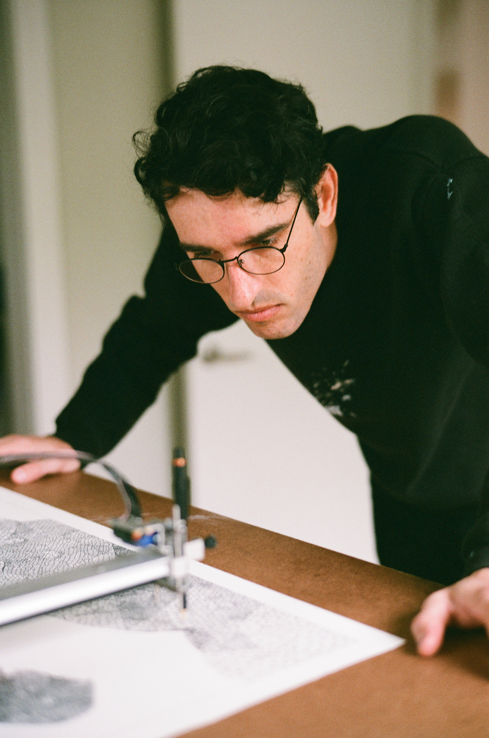 Tyler Hobbs working with a plotter, a programmable robot holding a pencil