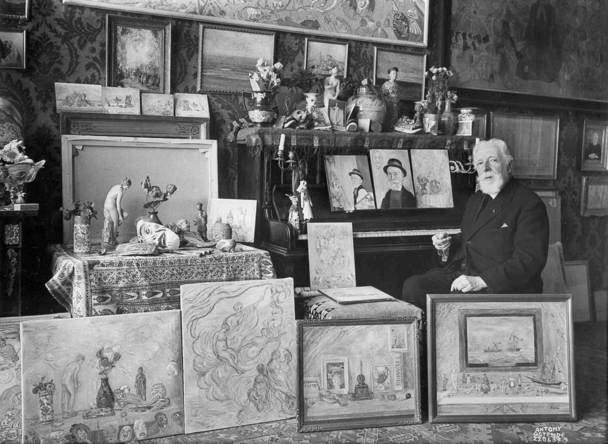 James Ensor in his Ostend studio with a row of late still lifes and self-portraits, 1937. Mu.ZEE, City of Ostend Collection