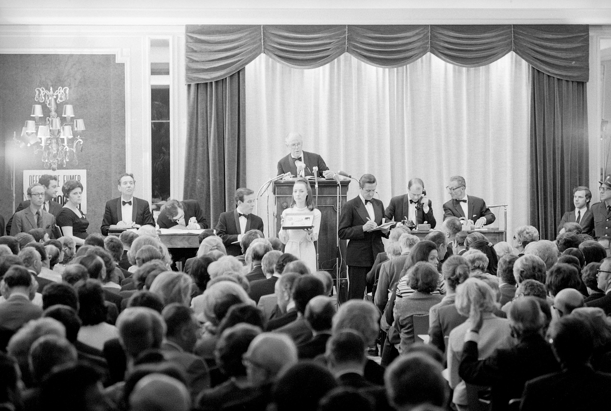 The inaugural Magnificent Jewels sale in Geneva, 1969, with then Christie's Chairman Peter Chance at the rostrum. The auction achieved a total of CHF 12.7 million, with the emerald and diamond clip brooch selling to Van Cleef and Arpels for CHF 900,000