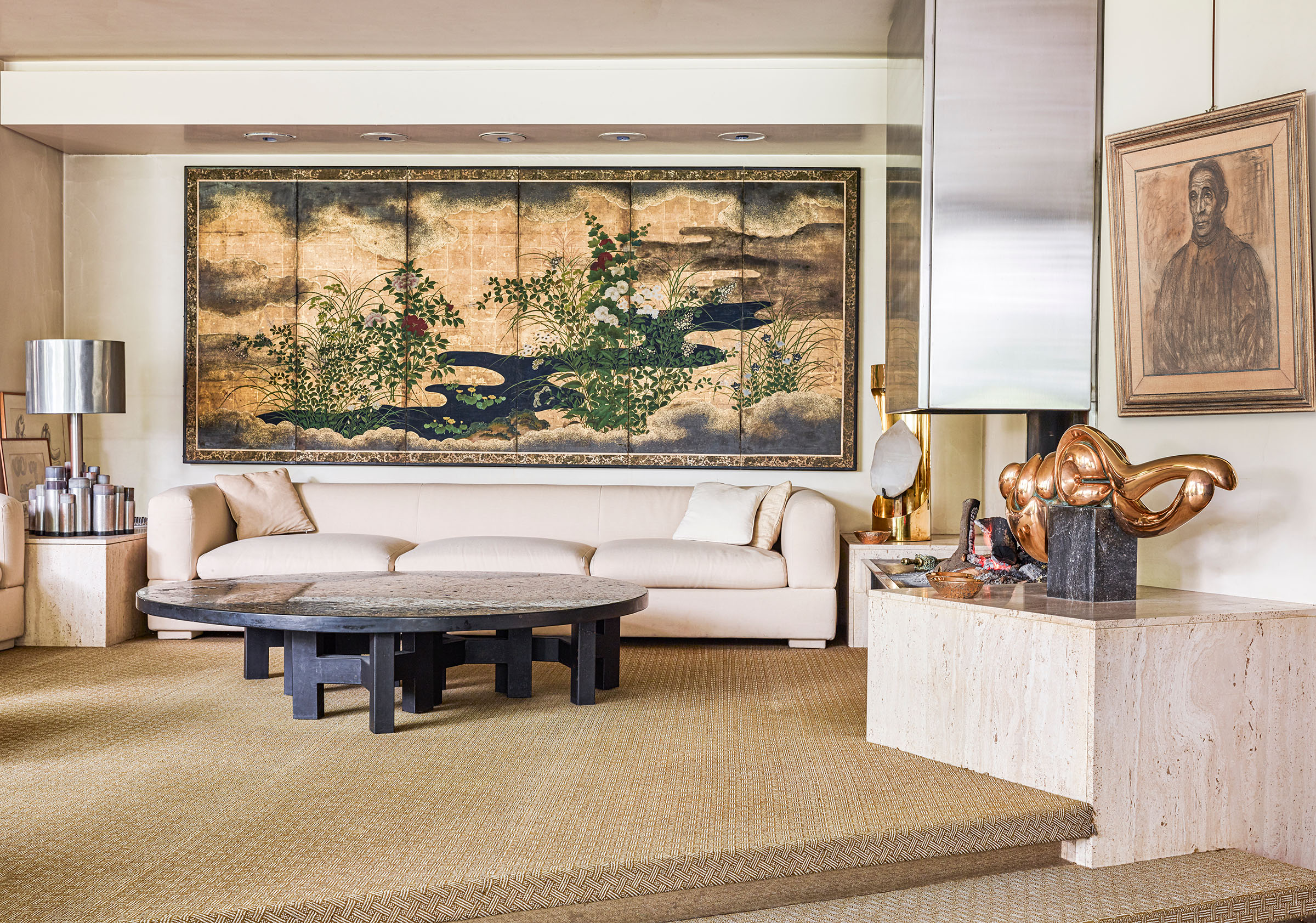 Spanning one length of the sitting room is a six-fold gold leaf Japanese screen from the Edo period (Estimate: €20,000-40,000), which is flanked by two circa 1970 table lamps by Ado Chale: left, in metal and agate (€5,000-7,000), and right, brass and rock crystal (€3,000-5,000). In the foreground is a coffee table inlaid with Ceylon ruby, resin and hematite, also by Chale, circa 1970 (€25,000-35,000), and a bronze and granite sculpture, L'endormie II, from 1972 (€6,000-8,000). On the wall is a 1922 charcoal and pastel work by Albert Servaes, Portrait du jardinier Jan (€1,000-1,500). All offered in The Onzea-Govaerts Collection - curated by Axel Vervoordt on 27 March 2025 at Christie's in Paris