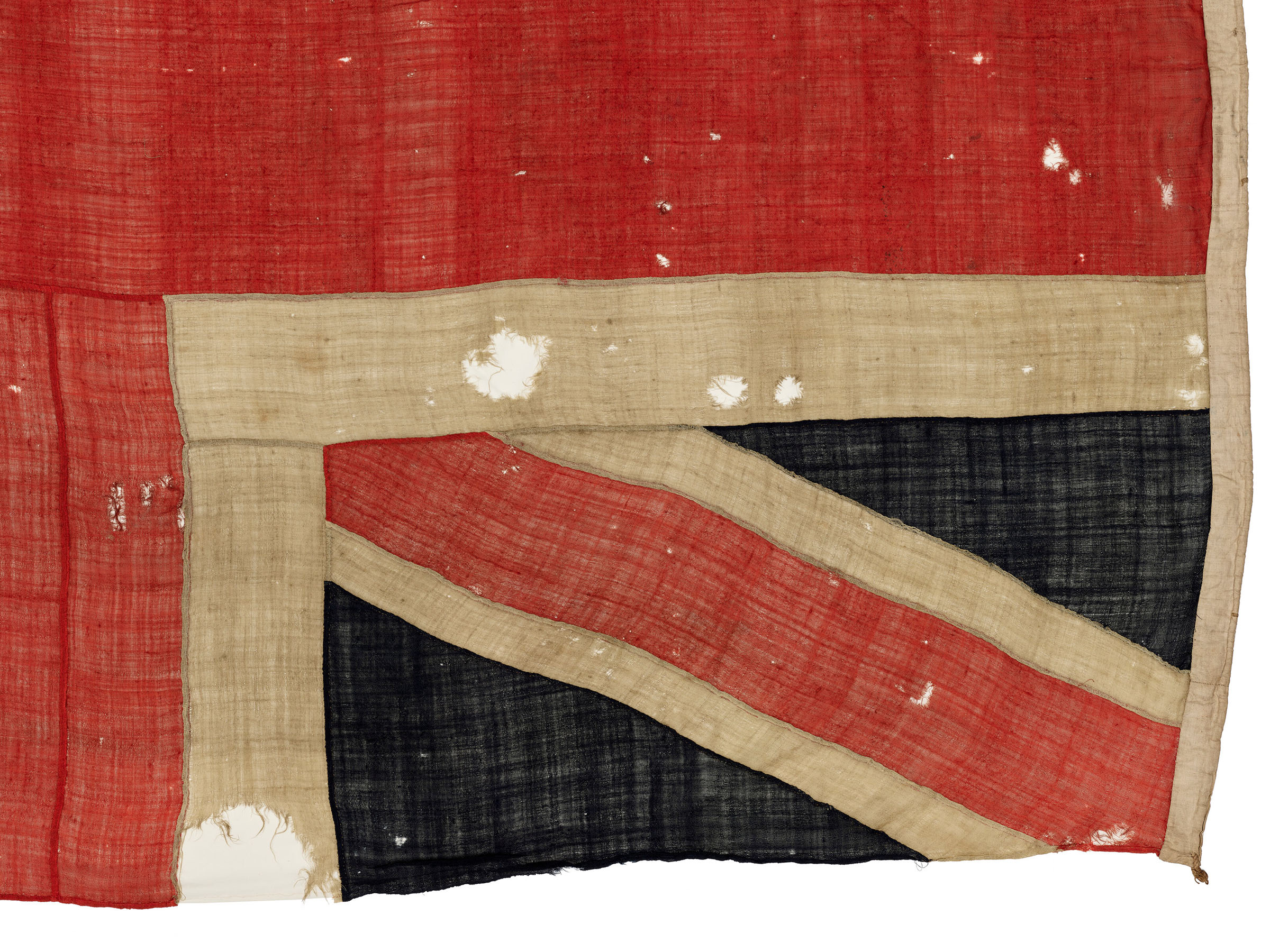 A detail of the Union Jack flown from HMS Spartiate at the Battle of Trafalgar, 21 October 1805, offered in The Exceptional Sale on 1 July 2025 at Christie's in London. Microscopic analysis has revealed shards of cannonball shrapnel embedded in the flag’s woven cloth, especially around the half-moon-shaped hole at the edge, which is likely the 'footprint' from a round. Similarly, surviving wooden splinters corroborate the details of the damage Spartiate sustained in combat