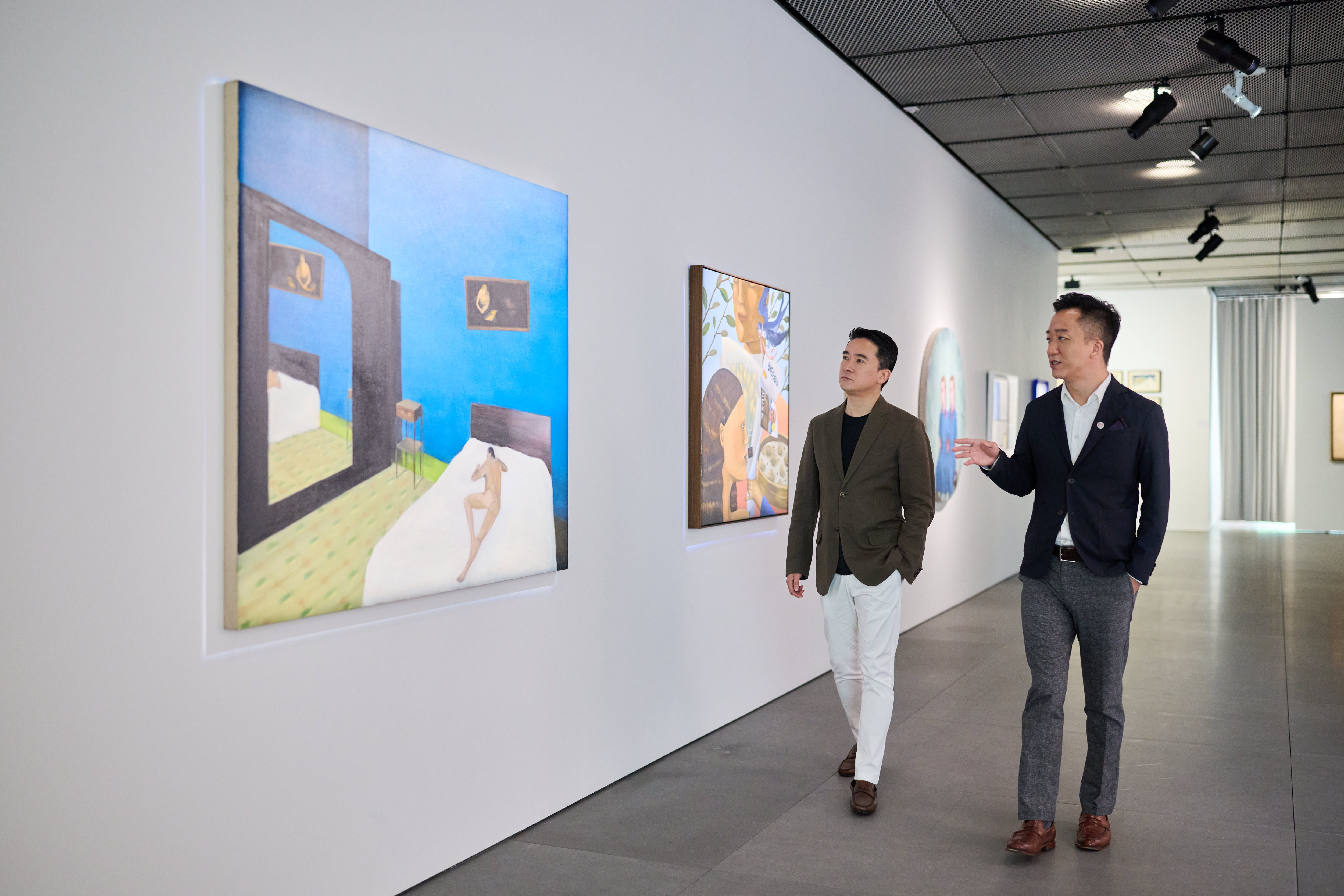 李小明與鄭景康在佳士得The Henderson亞太區總部藝術空間中一同欣賞二十及二十一世紀拍賣預展。藝術作品:(圖左)張英楠,《反射》,油彩 麻布,130 x 60公分(51 1/8 x 63英寸),2006年作。估價:港元150,000-250,000。(圖右)陳柏豪,《小拇指》,油彩 畫布,110 x 110.5公分(43 ¼ x 43 ½英寸),2022年作。估價:港元150,000-300,000。作品均將於2025年9月27日在佳士得香港二十一世紀日間拍賣中呈獻