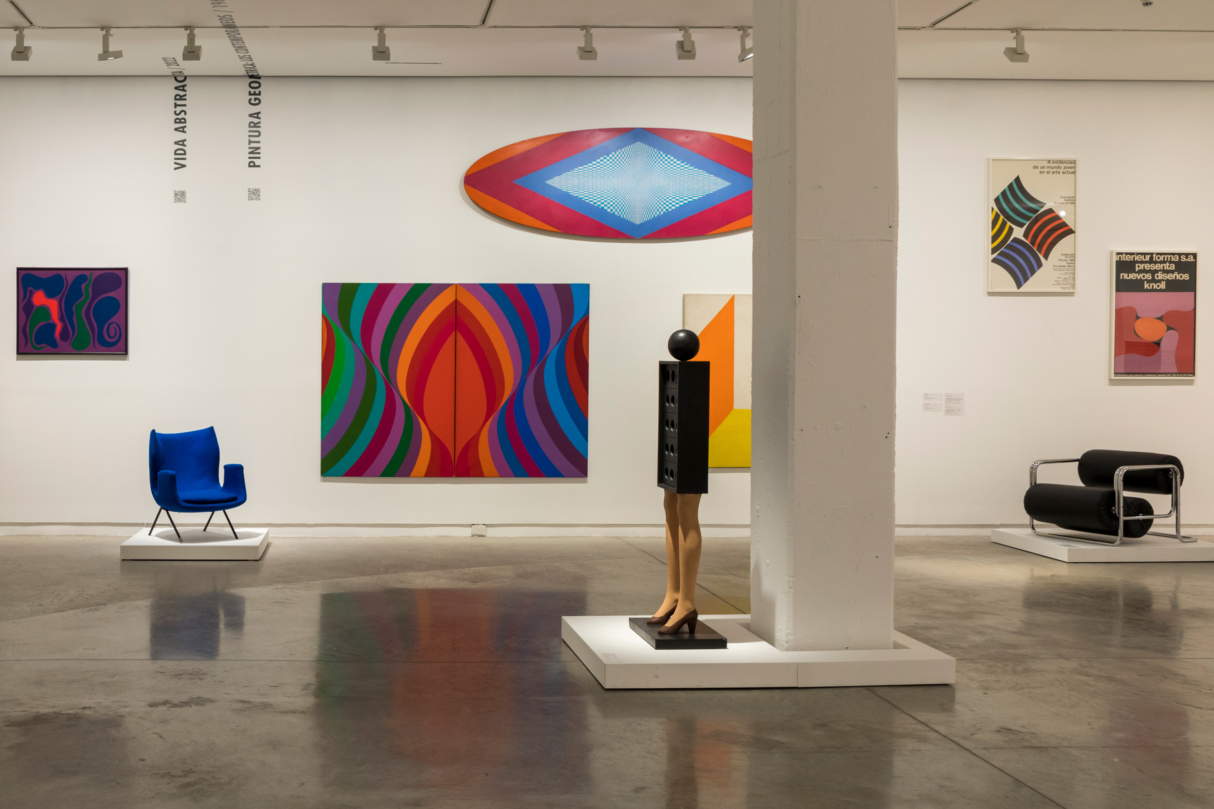 A modern art gallery displaying vivid abstract paintings and stylish furniture, with a mannequin sculpture in the foreground.