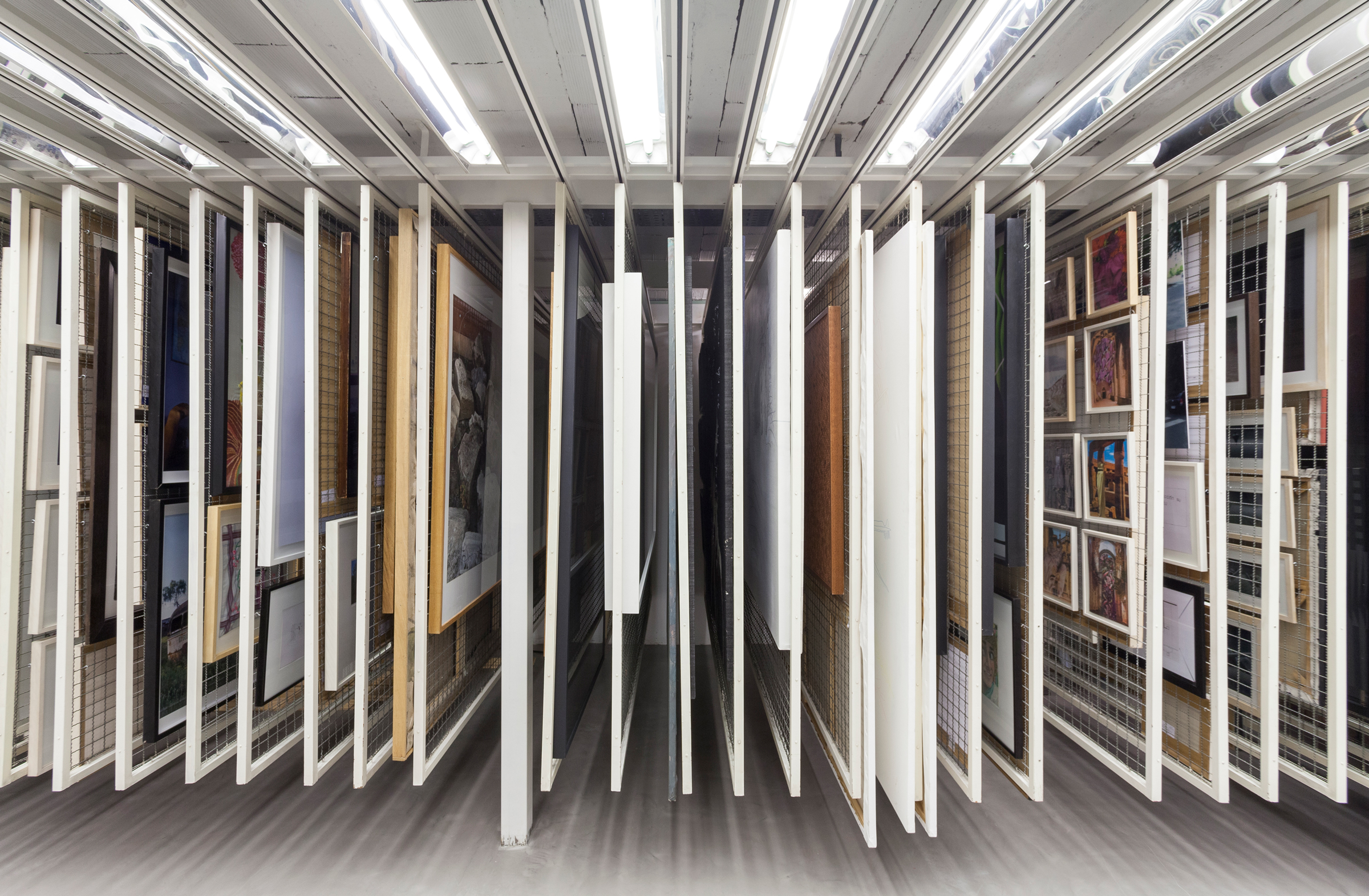 Interior view of a modern storage system with various framed artworks arranged in sliding panels.
