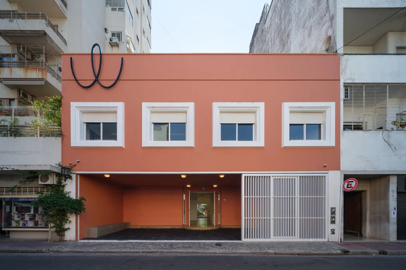 A modern building with a vibrant orange facade, featuring a unique circular design above three white-framed windows.
