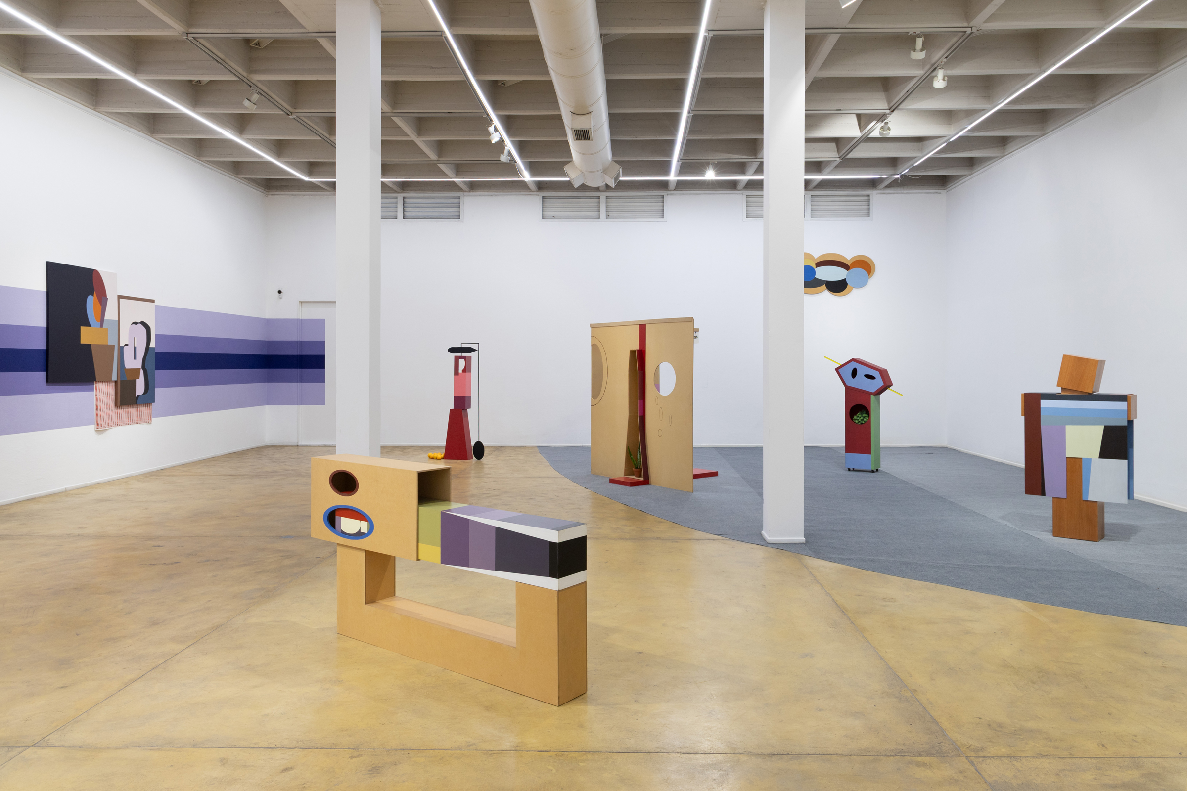 Modern art gallery displaying colorful, abstract geometric sculptures and paintings.