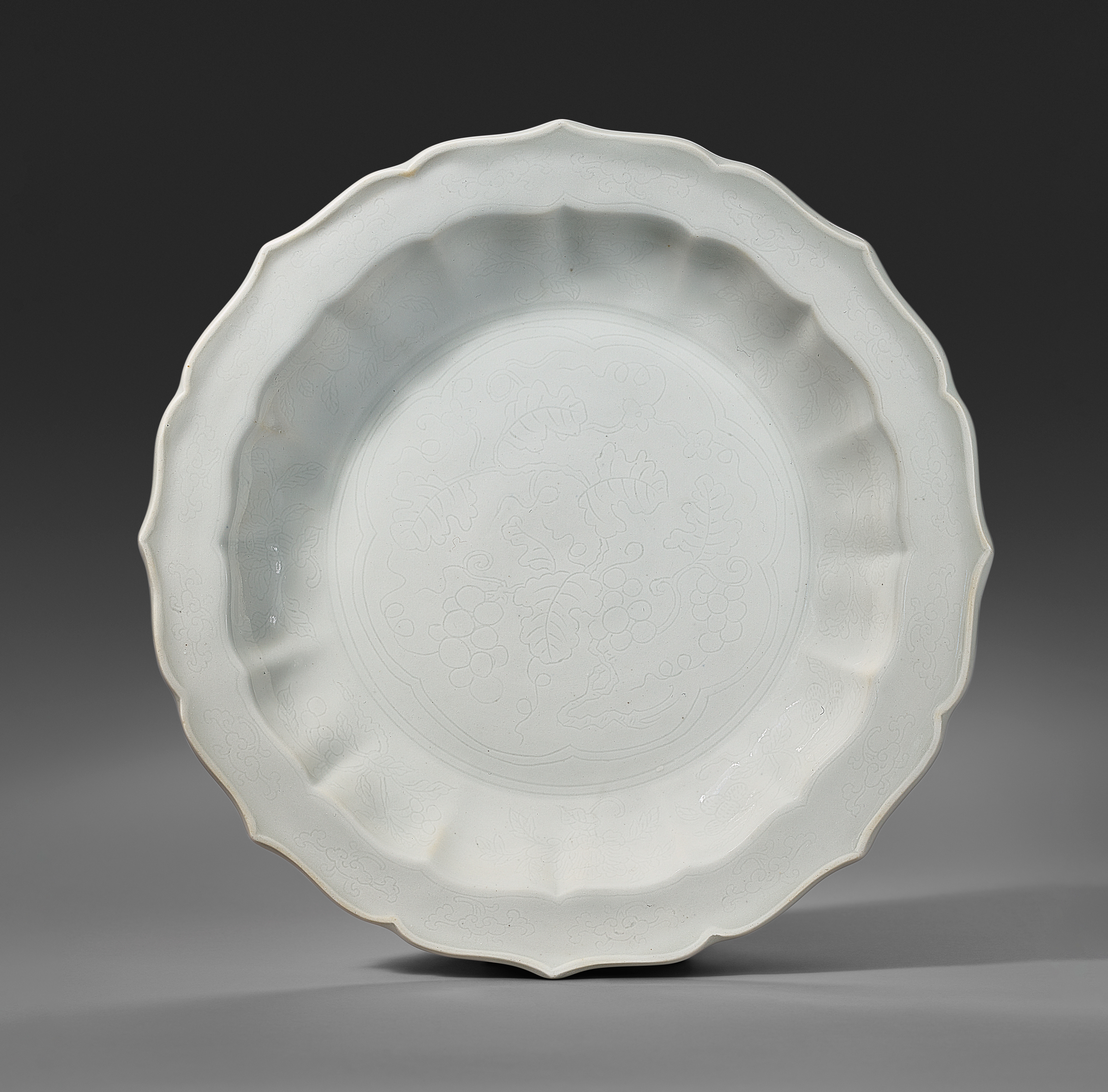 A very rare and superb incised tianbai-glazed barbed ‘grapevine’ dish from the Yongle period, 1403–1424. 7⅞ in (20 cm) diameter. Estimate: $200,000–300,000. Offered in Important Chinese Furniture and Works of Art on 18 September 2025 at Christie’s in New York