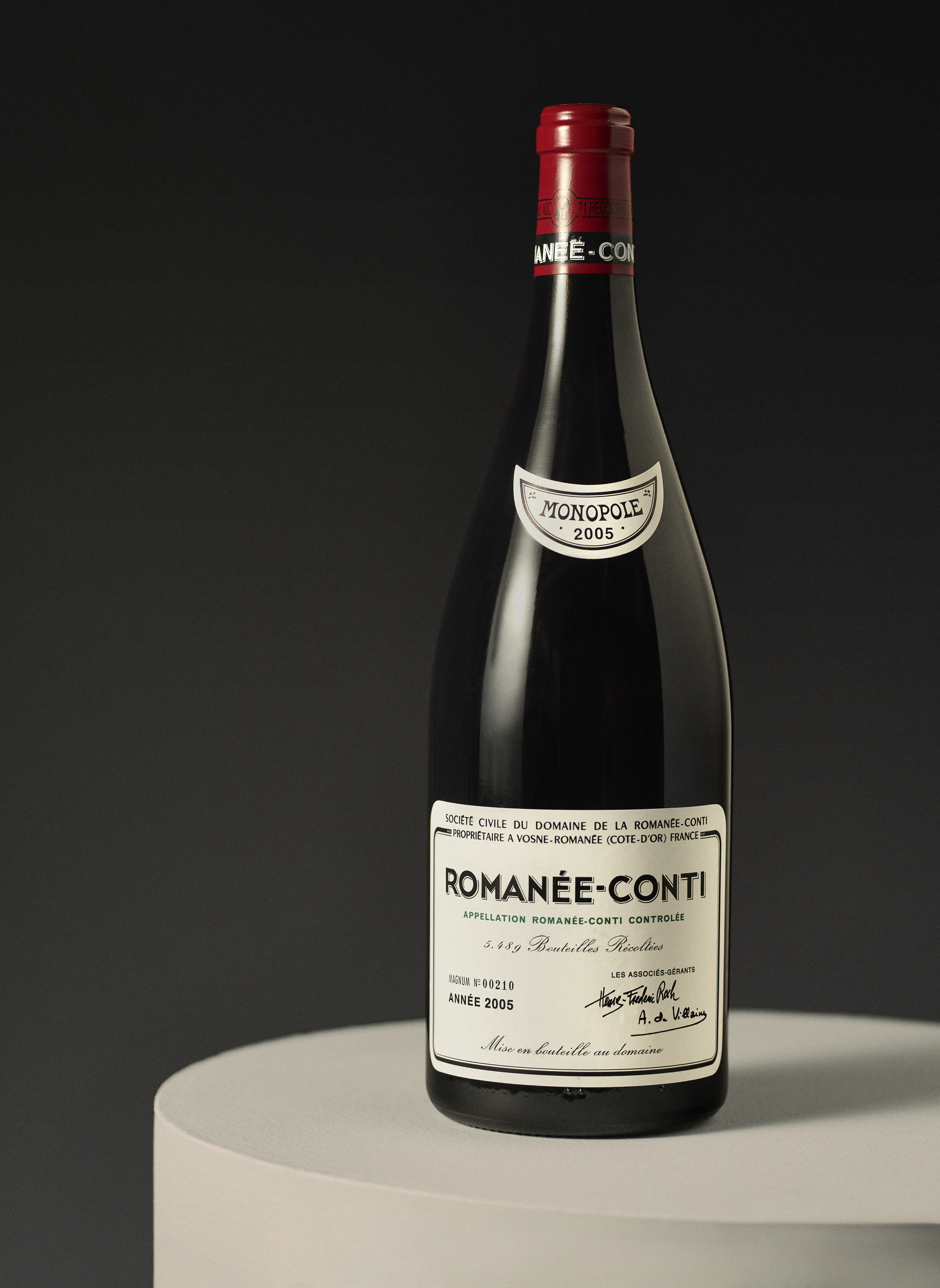 A bottle of Romanée-Conti 2005 wine, marked "Monopole," displayed against a grey background.