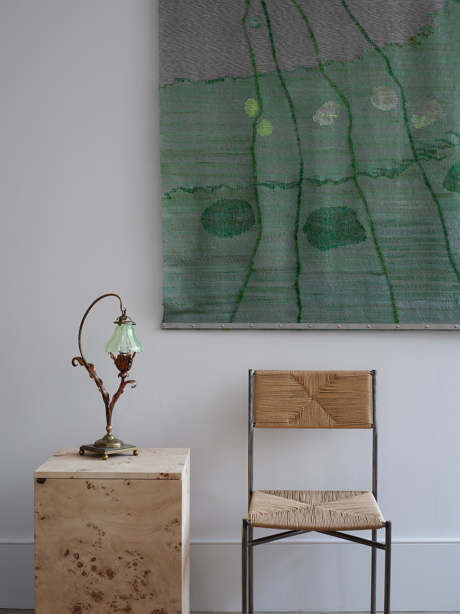 A Benson Arts and Crafts lamp sits on a Floating Side Cabinet by Rose Uniacke, alongside the designer's Simple Dining Chair. On the wall is Simone Prouve, Panneau 020513, 2013