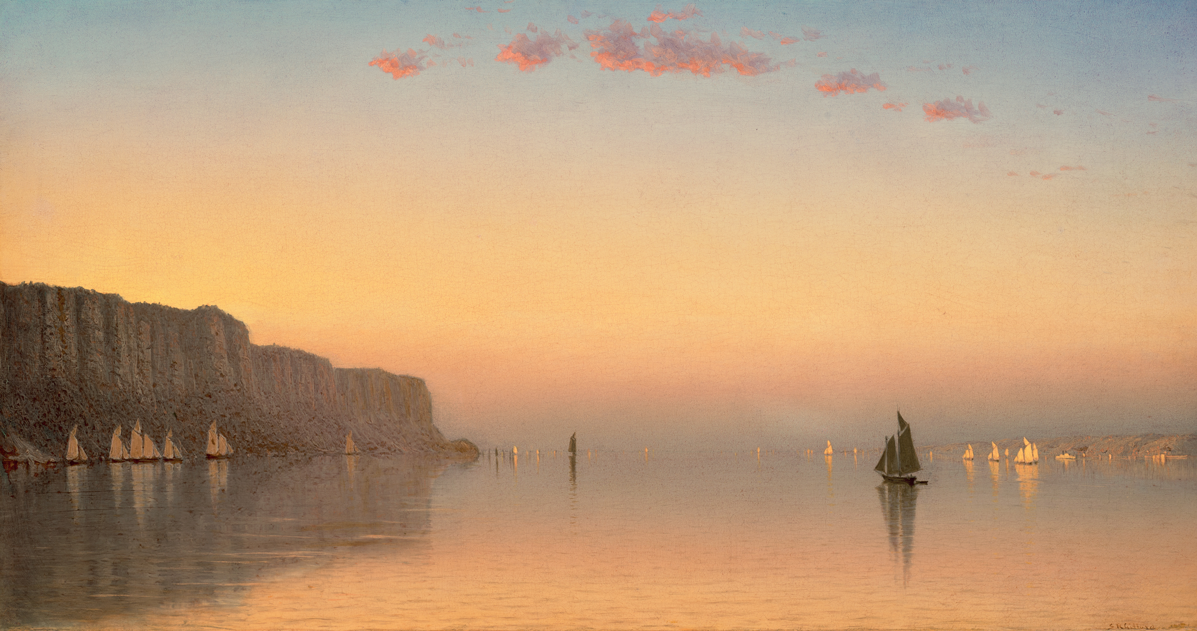 Sailing boats on a tranquil sea at sunset, with a cliff on the left and soft pink clouds above.