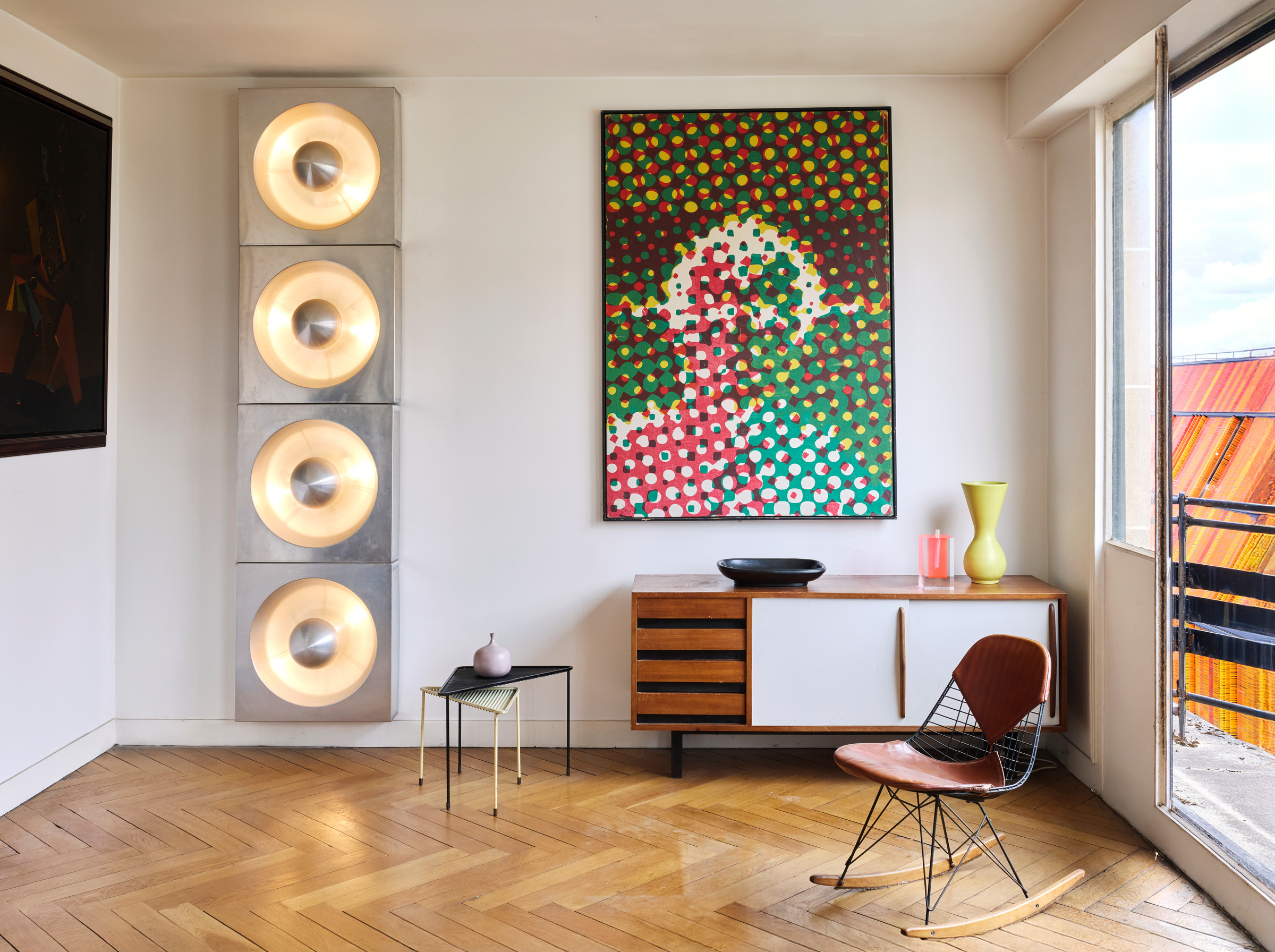 From left: a set of four Spiegel wall lights by Verner Panton, 1968-69; a pair of nesting Triangle tables by Mathieu Mategot, circa 1950 with one of a group of bottles, vases and a pebble, circa 1960-70, by Jacques and Dani Ruelland. On the Charlotte Perriand Cansado sideboard, circa 1962, are ceramics by Georges Jouve and Pol Chambost, alongside a 1989 Soliflore Flower Vase #2 by Shiro Kuramata. The rocking chair is a Bikini RKR-2 by Charles and Ray Eames, circa 1955. All offered in Design, 1925-2025: la Modernite en Heritage on 26 November 2025 at Christie's in Paris