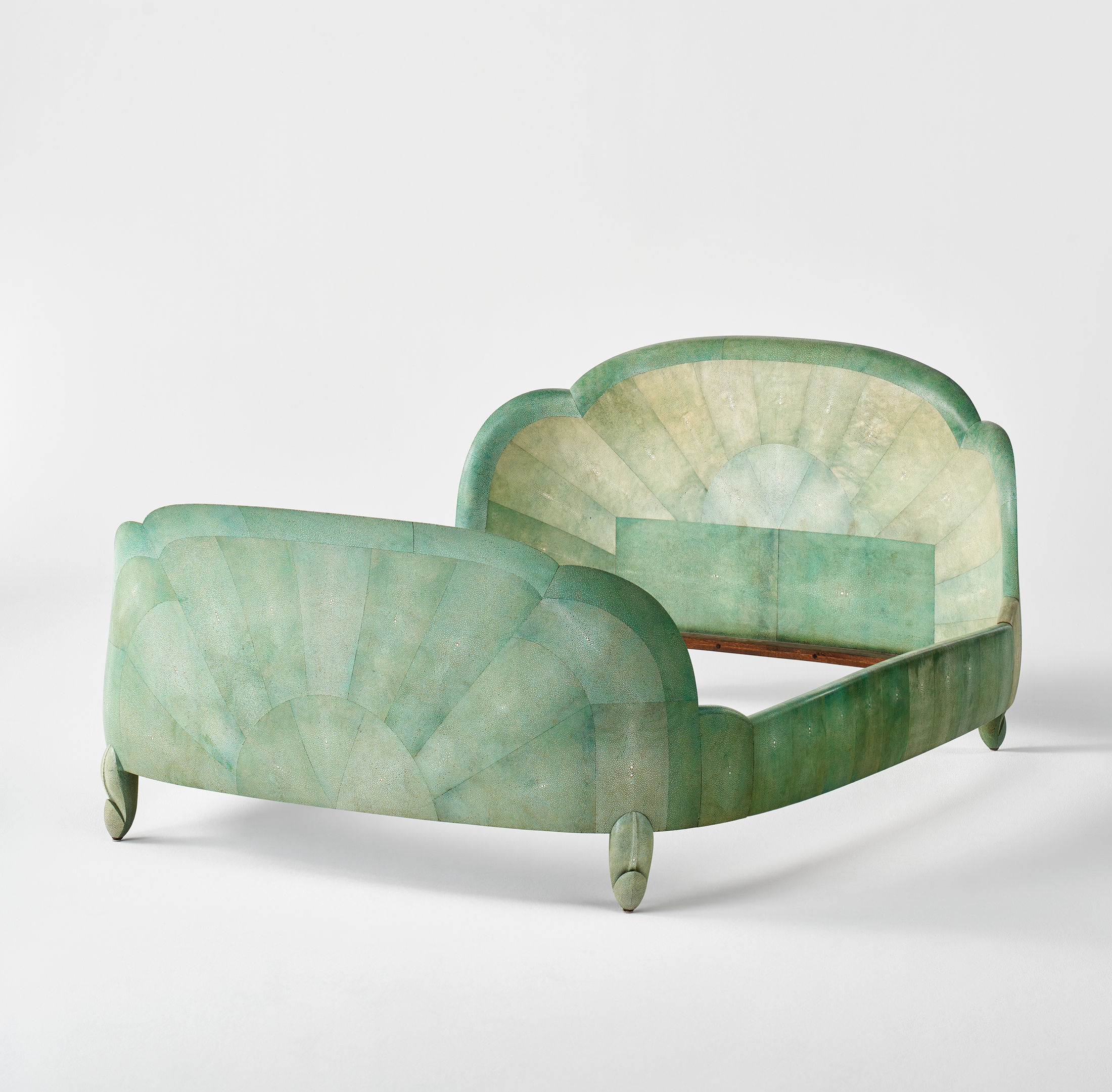 A green Art Deco style bed frame features a sunburst pattern on both the headboard and footboard, with curved edges and short legs.