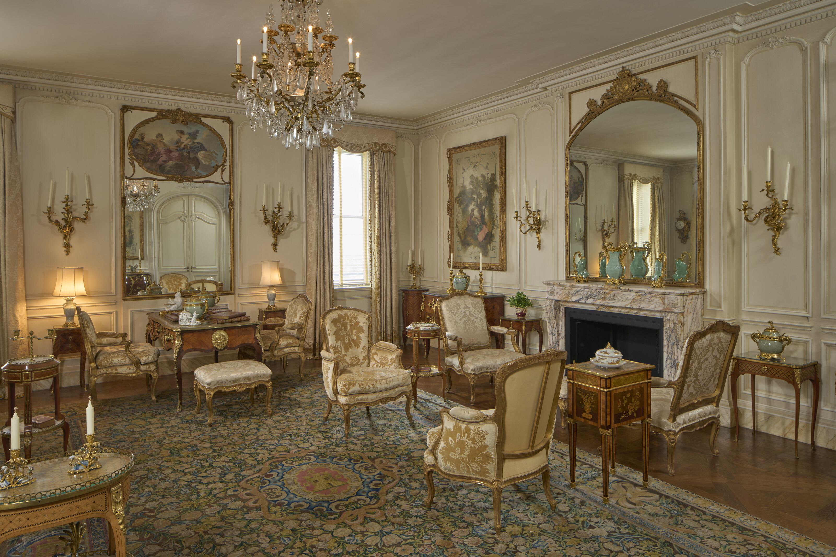 An elegant, classic living room features ornate furniture, chandeliers, and a large decorative rug.