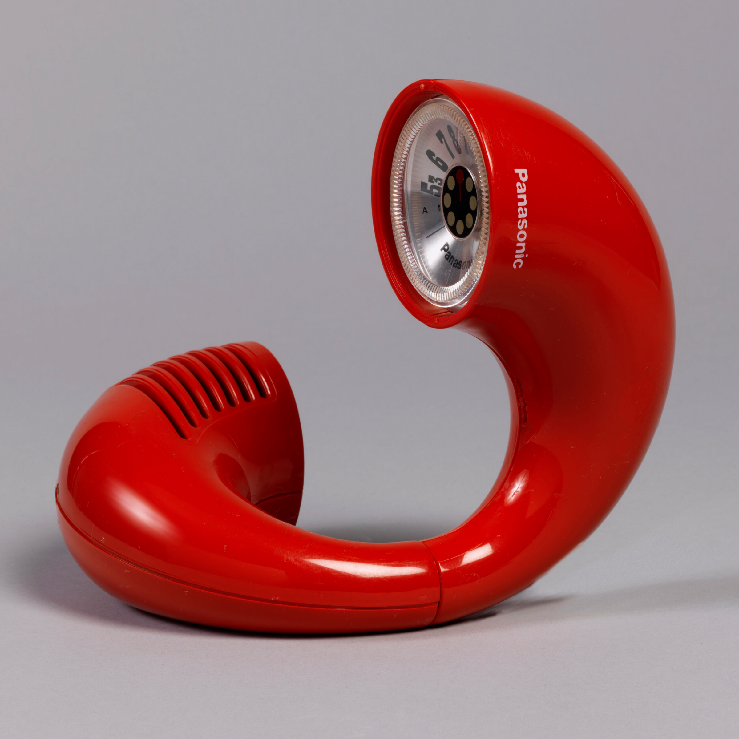 A retro red Panasonic telephone with a unique curved design is shown on a gray background.