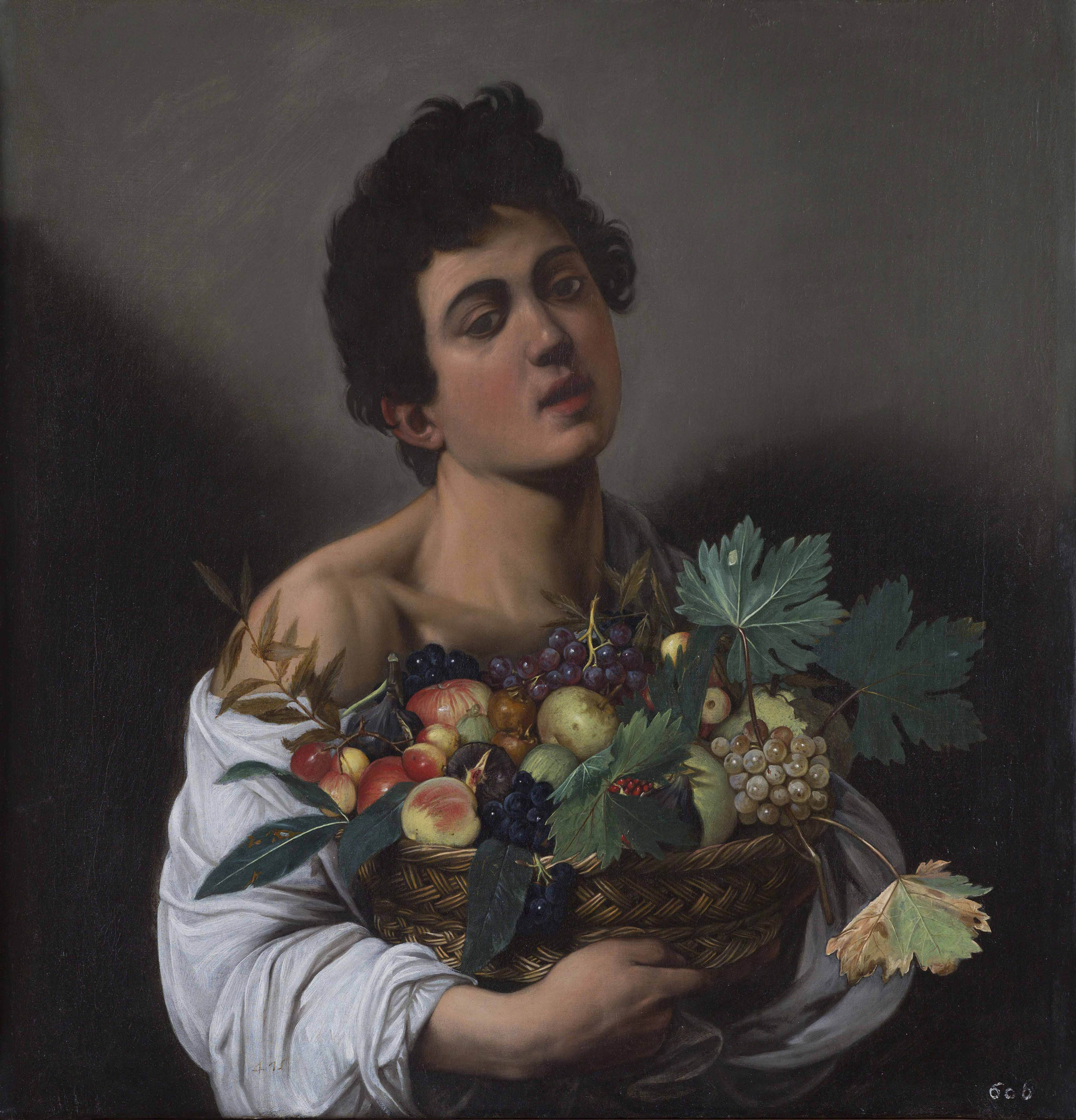 A person holds a large basket filled with various fruits, including grapes and apples.
