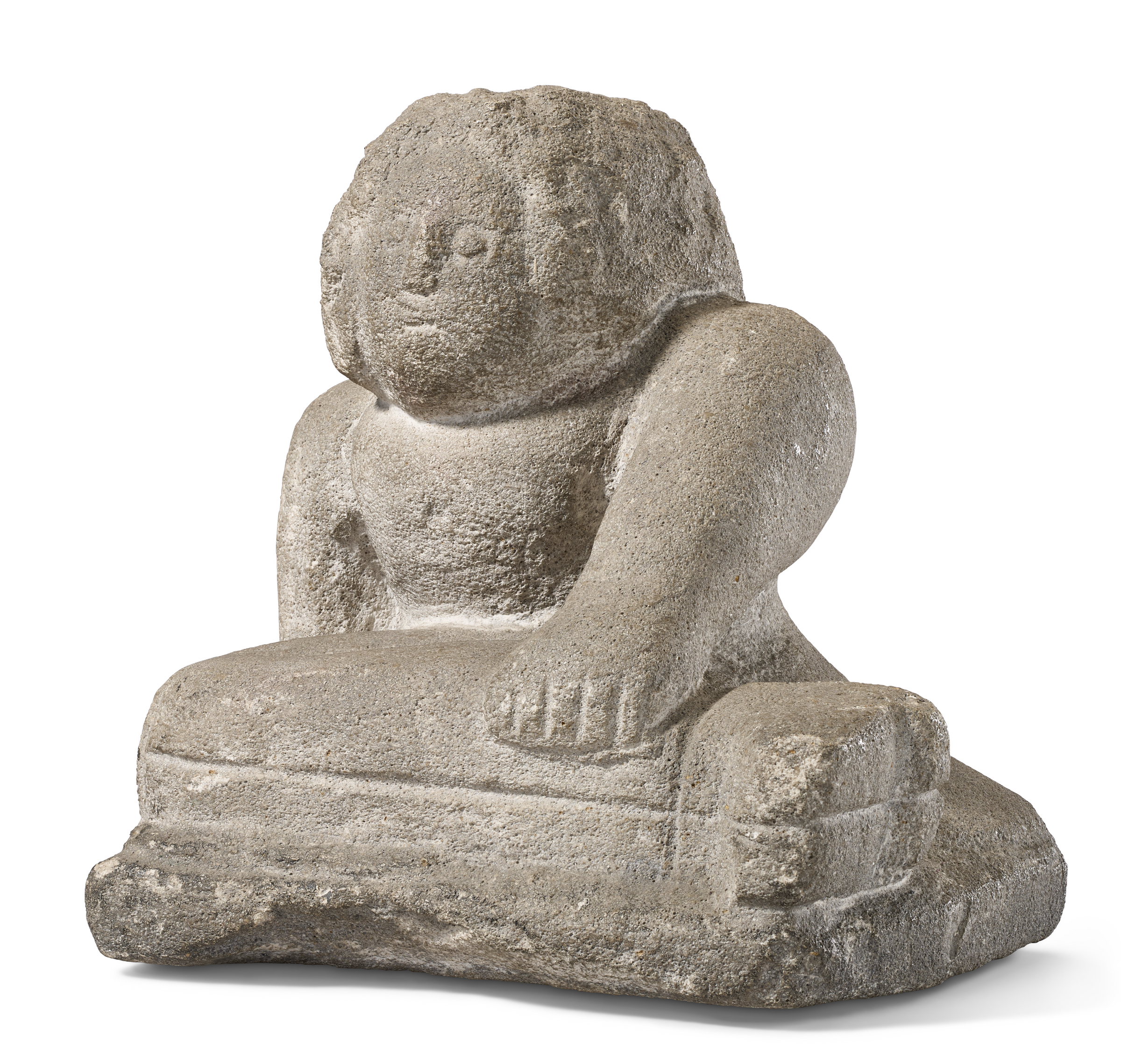 A stone sculpture of a seated figure with one arm resting on its knee.