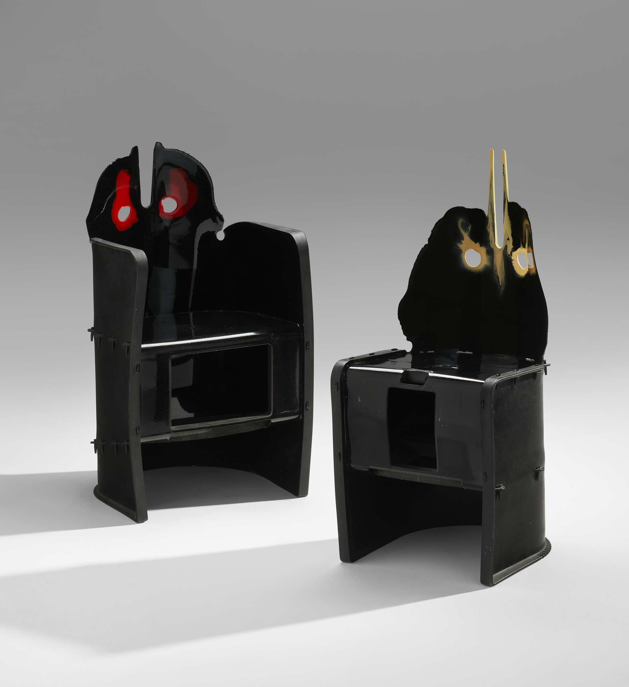 Two black chairs with abstract, face-like backrests and colorful eye details are shown.
