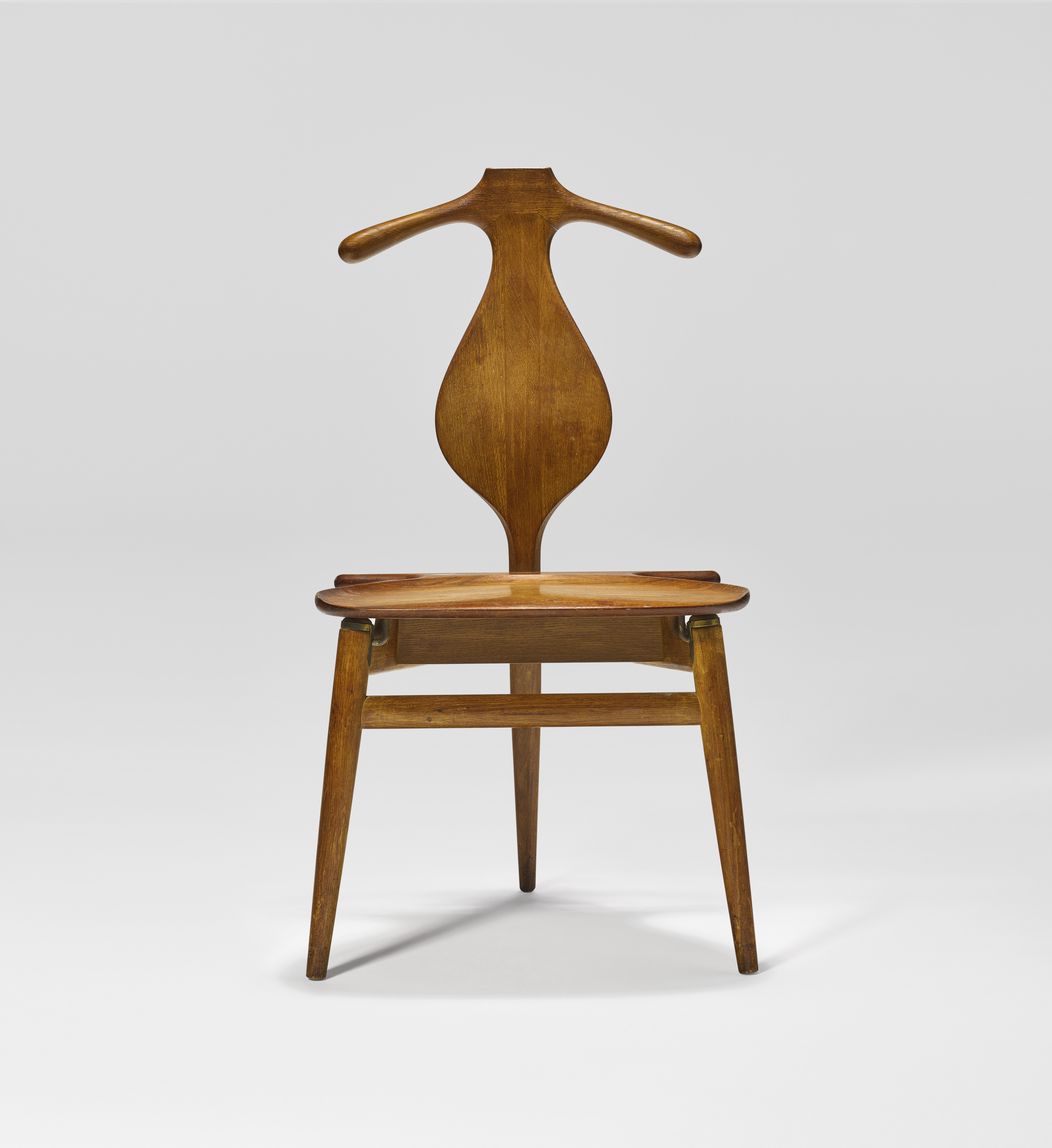 A wooden chair with a uniquely shaped back resembling a coat hanger and angled legs.