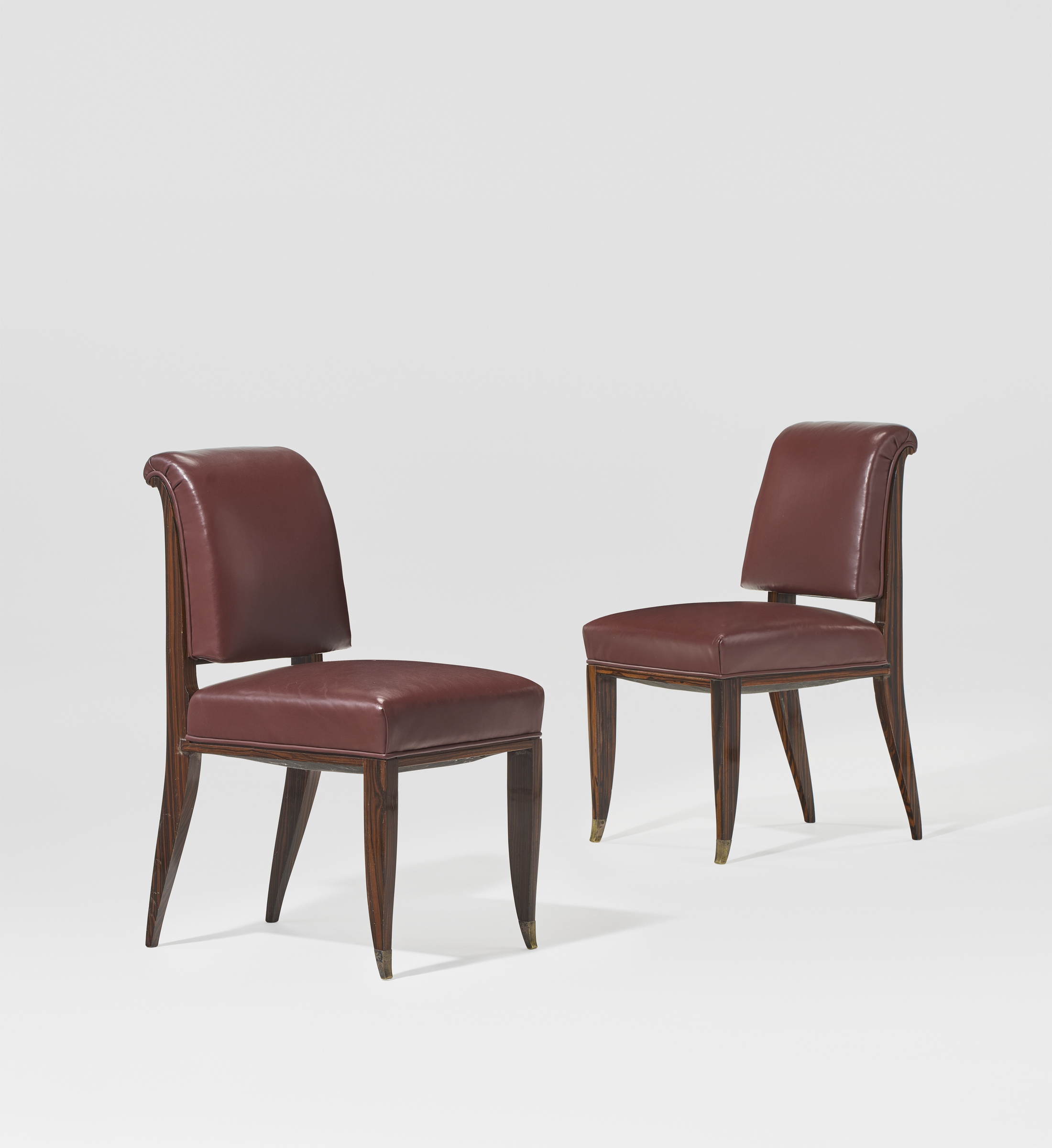 Two elegant chairs with curved wooden legs and burgundy leather upholstery are shown.