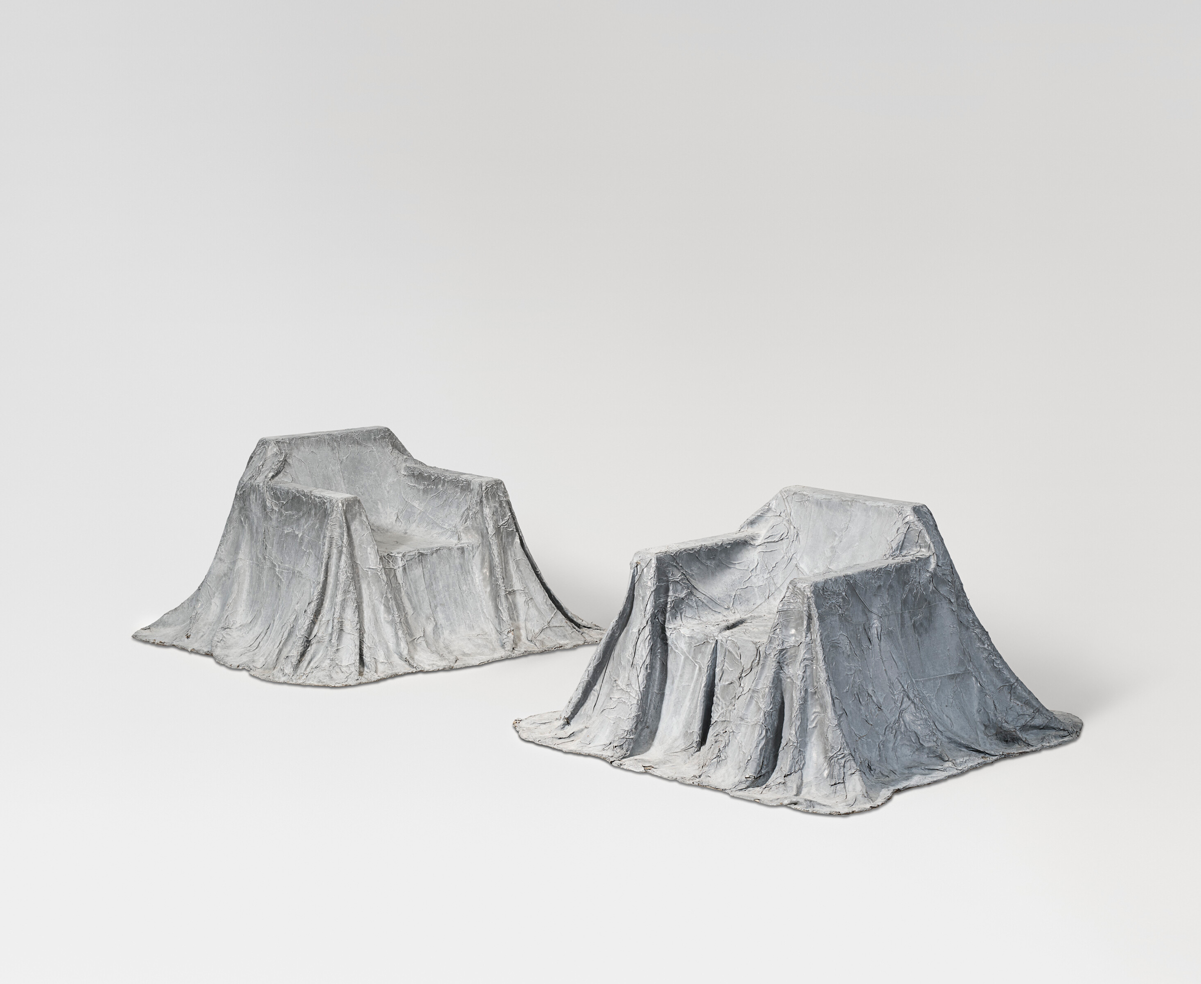Two gray armchairs appear to be draped in sculpted, textured cloth covers.