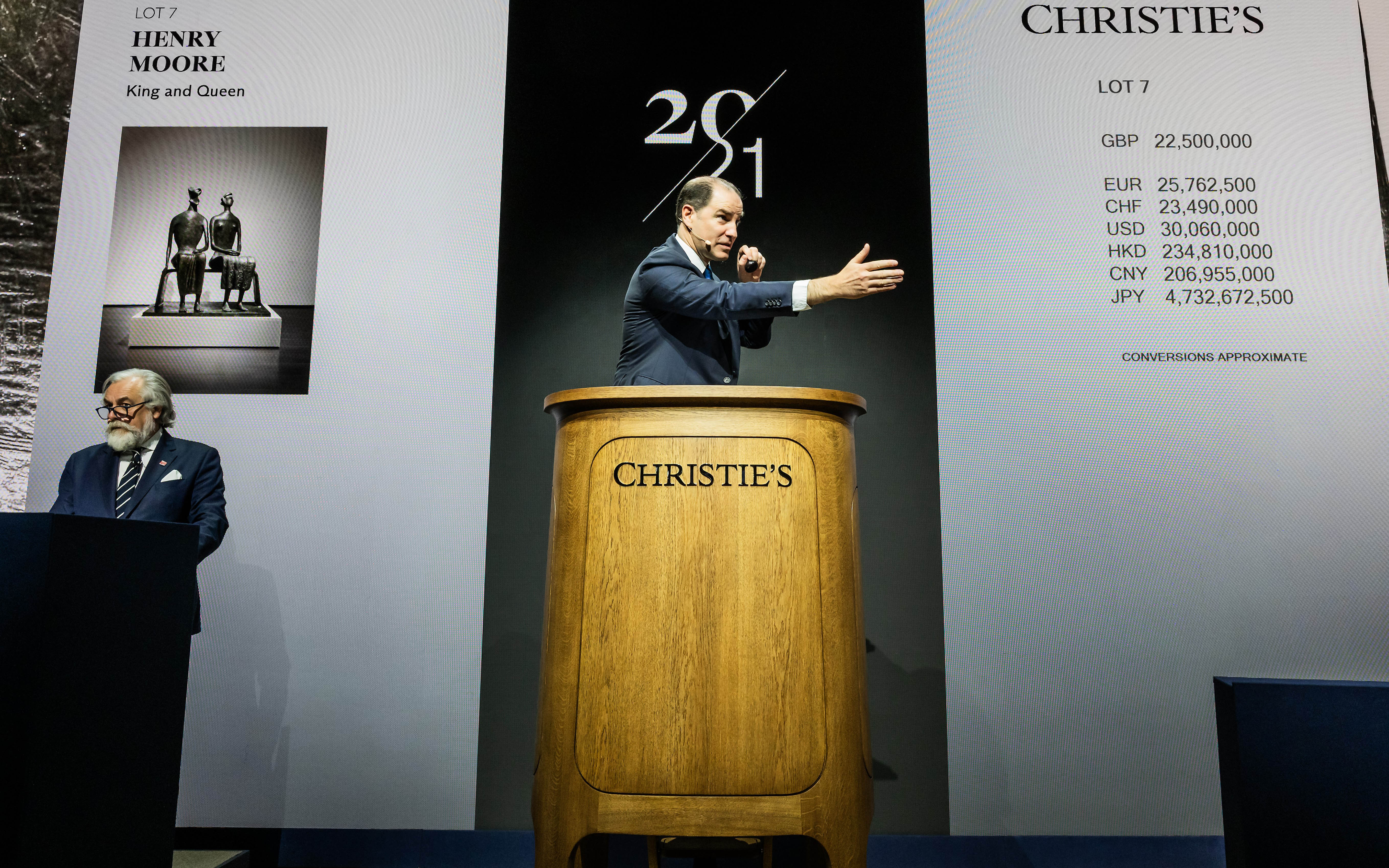 An auctioneer at Christie's is selling Henry Moore's "King and Queen" sculpture for Lot 7.