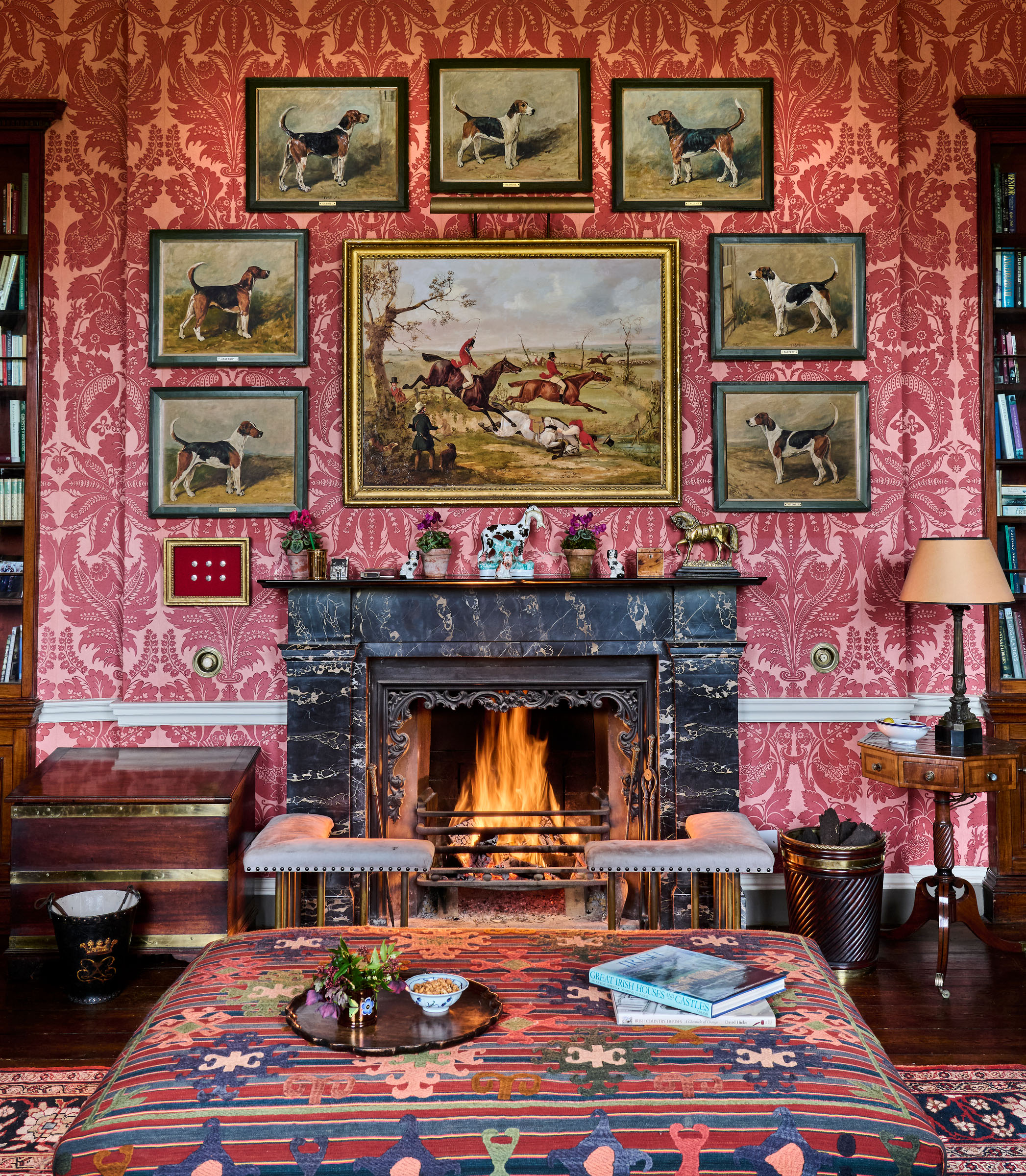 The Library: above the fireplace are seven portraits of hounds by John Emms; in front is a large upholstered ottoman by Serena Williams-Ellis; on the left is one of a set of five George III leather fire buckets painted with the monogram of the Dukes of Leinster. All offered in Collections: Including Ardbraccan House, Ireland and a Sicilian Palazzo, until 15 April 2026 at Christie's Online