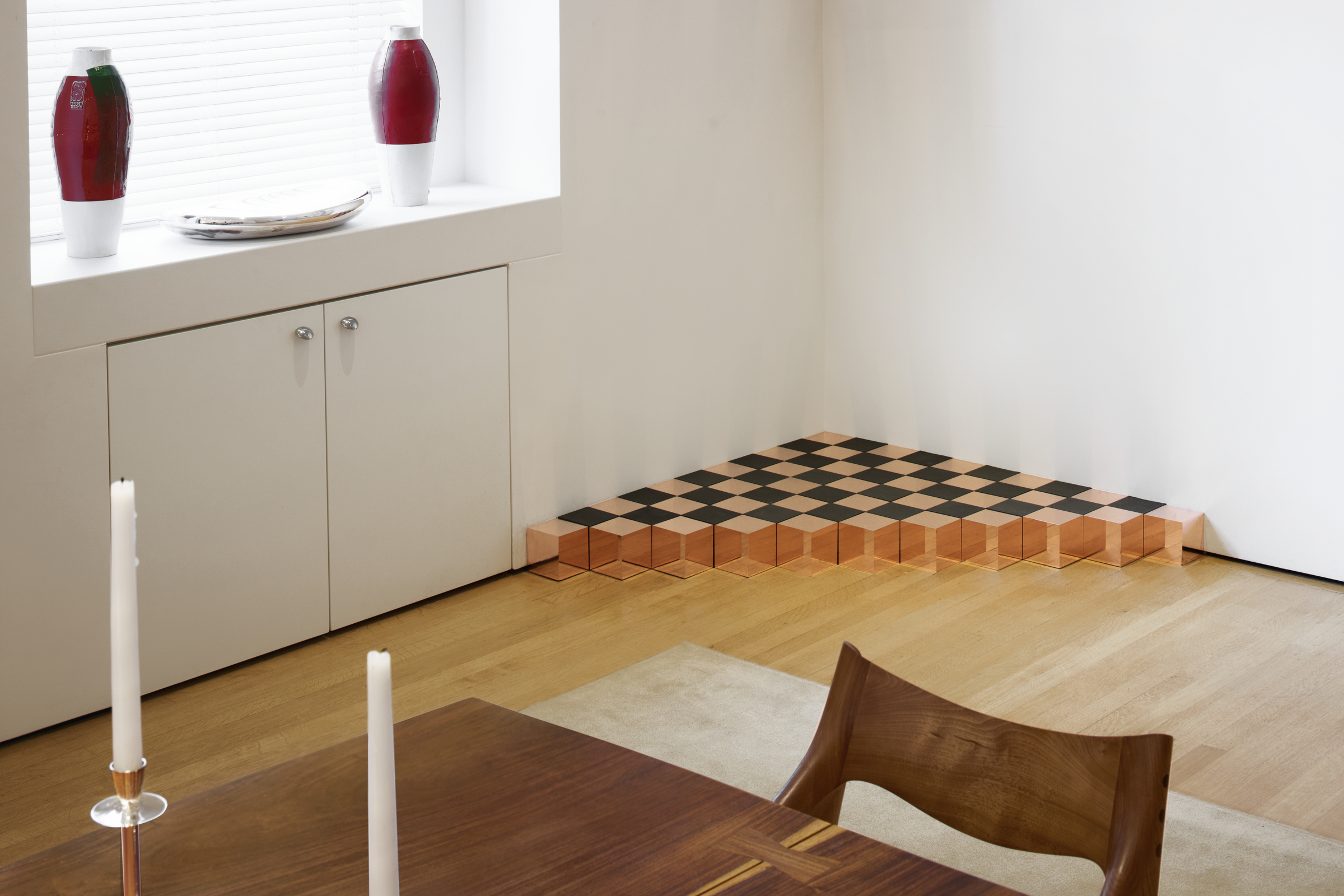 A modern room with wooden furniture and a corner checkerboard-patterned stepped platform.