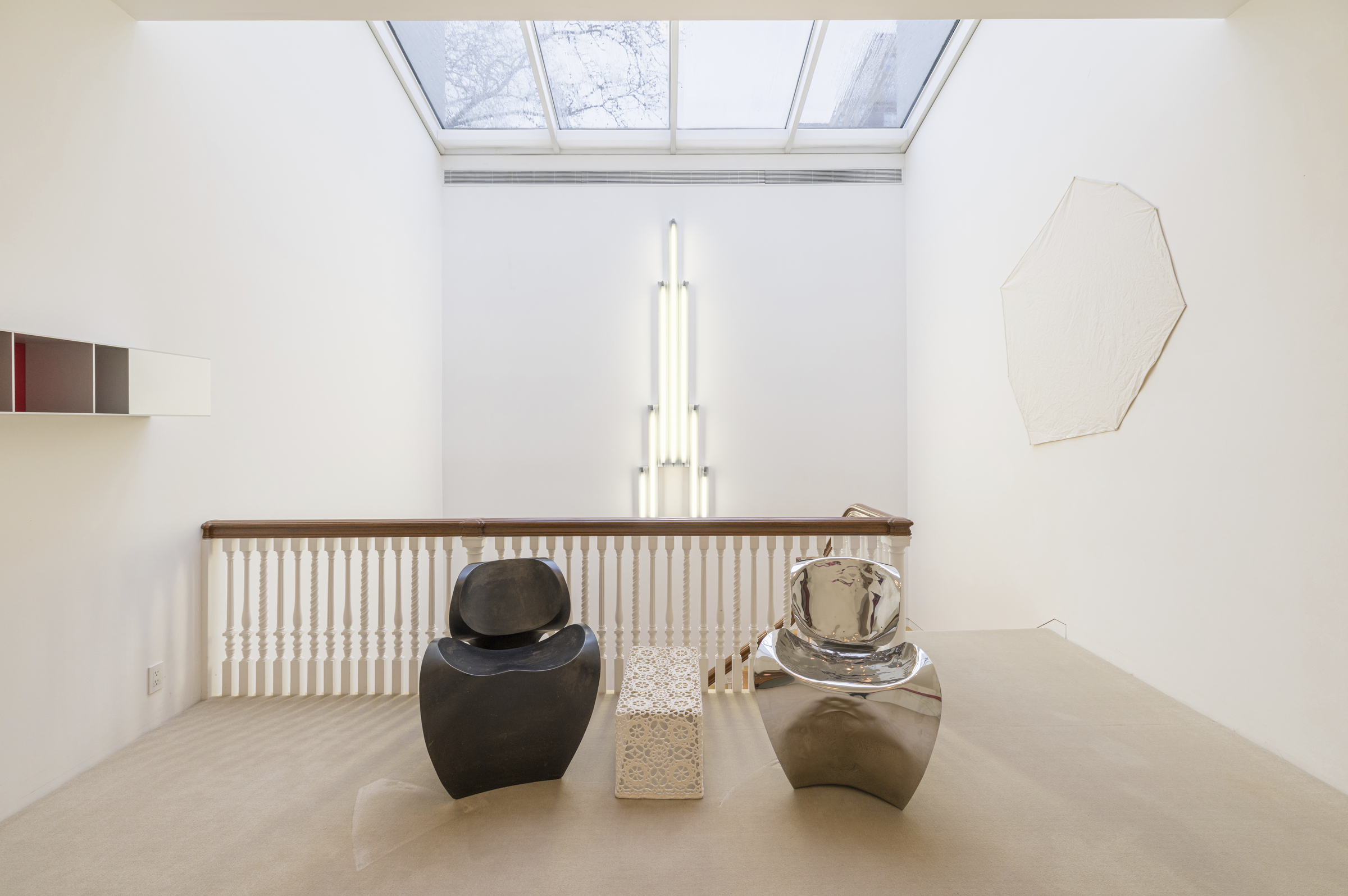 Two modern sculptural chairs and a geometric table are arranged in a minimalist, bright room.