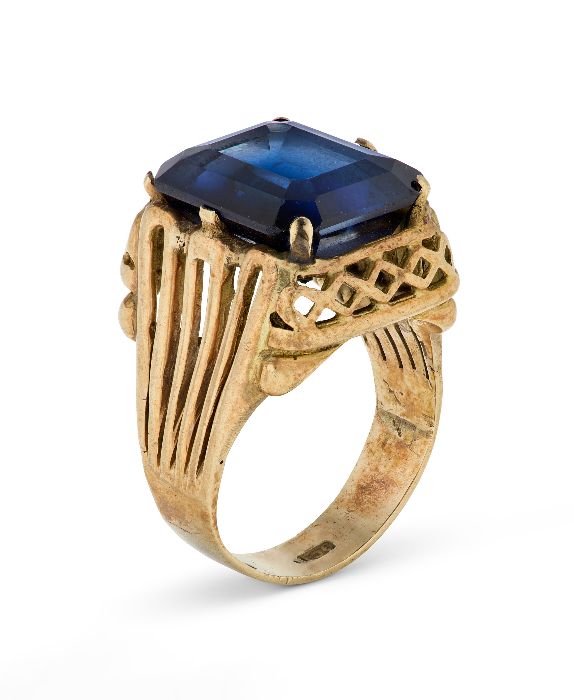 A gold ring with an ornate band, featuring a large, rectangular deep blue gemstone.