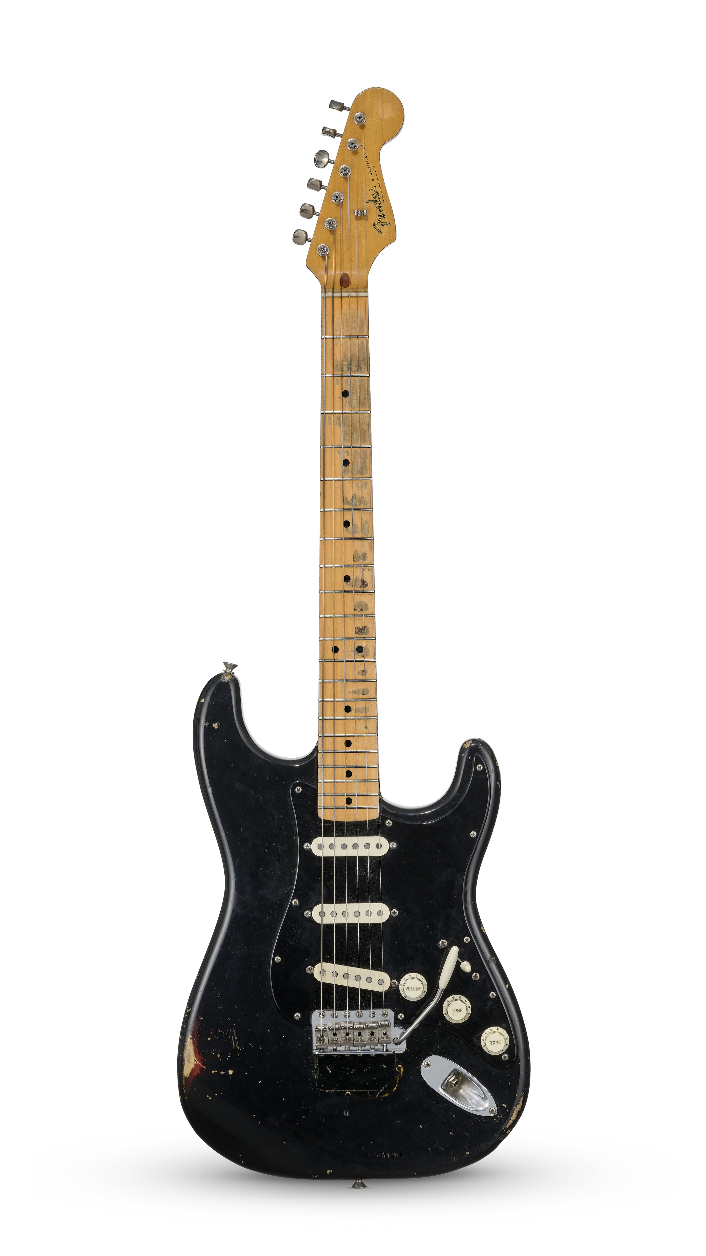 A worn black electric guitar with a maple neck and three white pickups.