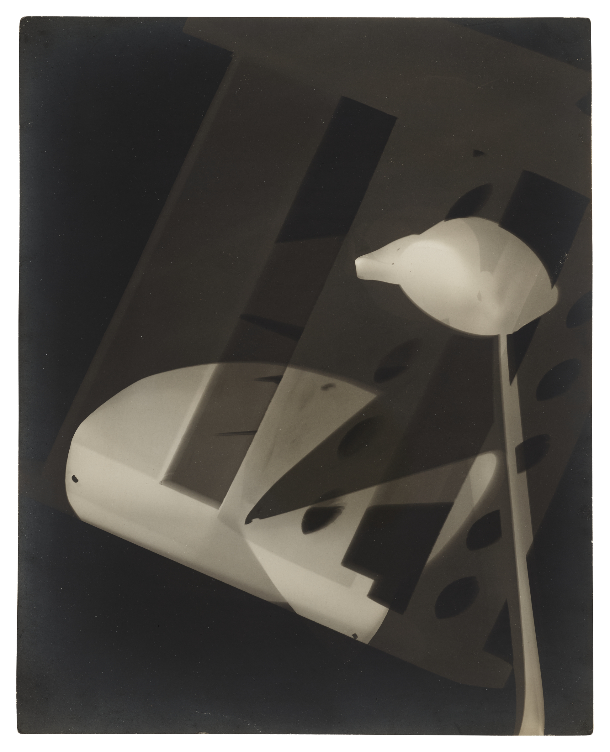 An abstract black and white photogram with overlapping geometric and organic shapes.