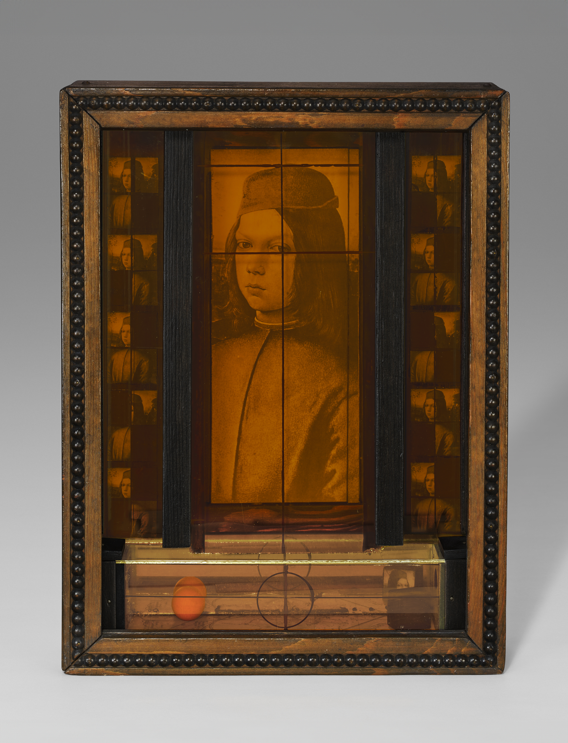 A framed mixed media artwork features a sepia-toned image and geometric elements behind glass.