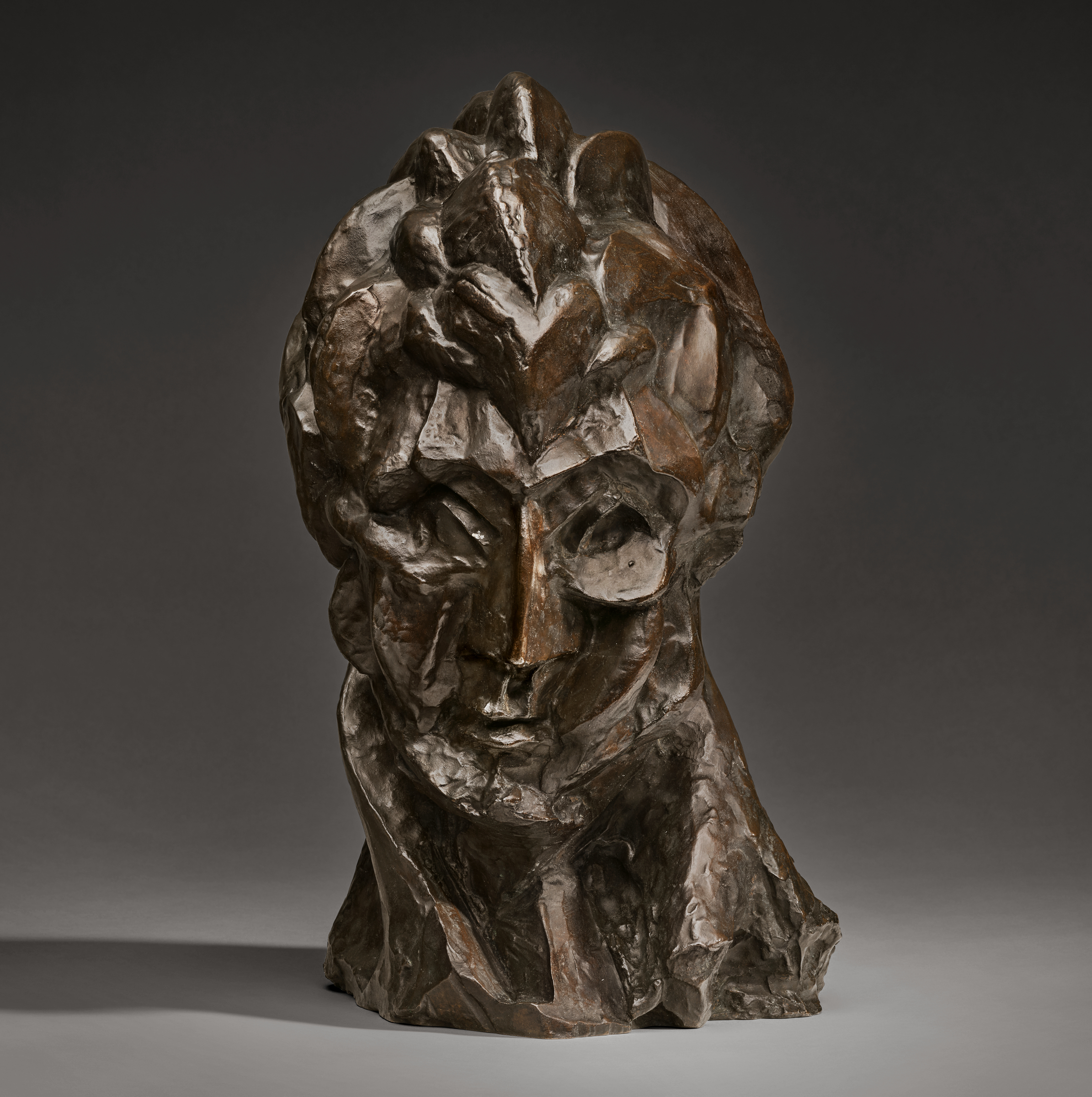 A bronze abstract sculpture with rough, textured surfaces on a plain background.