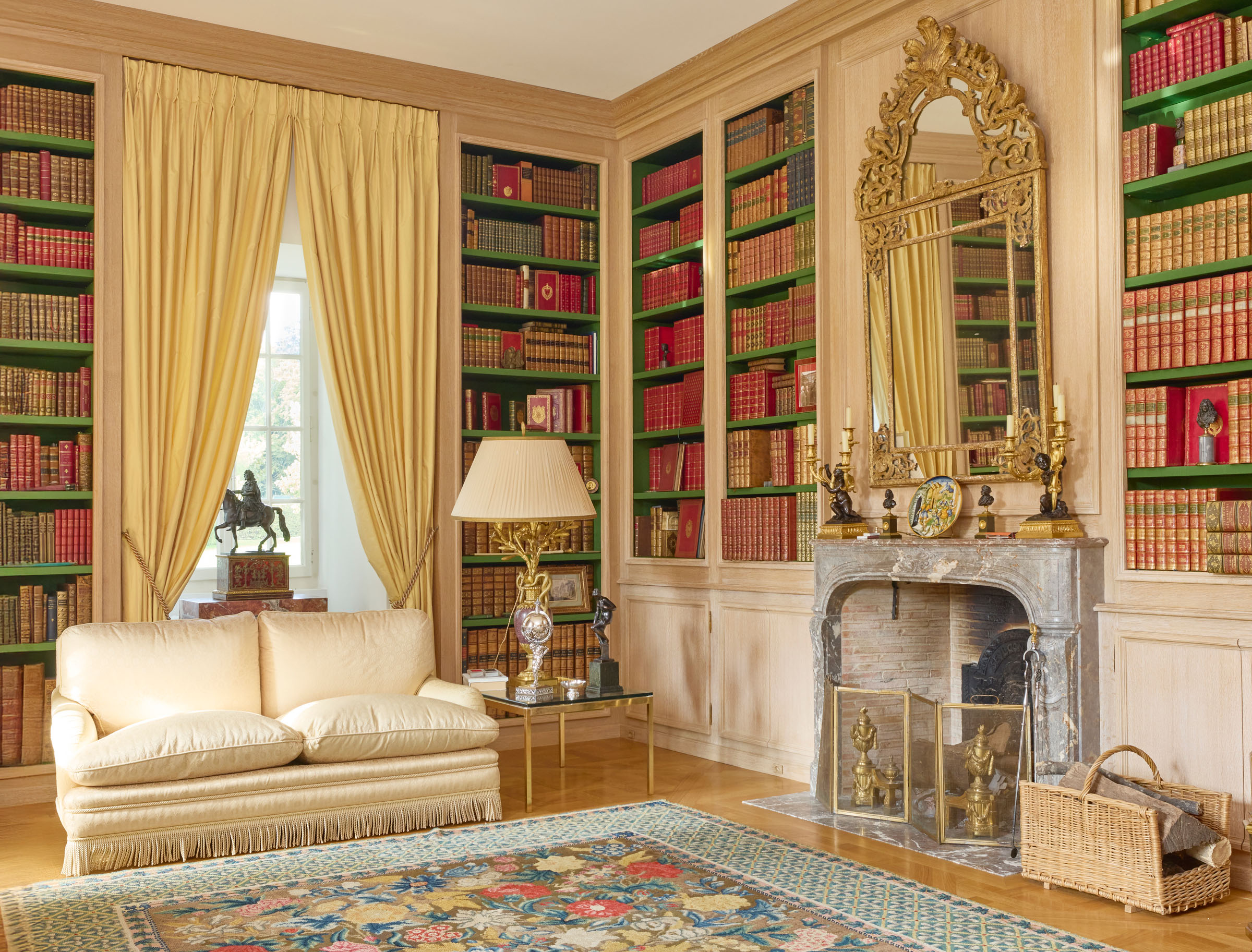 The library of Chateau de Tournay, a light and airy room with views across the gardens, is decorated in neutral tones that complement the marquetry floor and bespoke bookshelves